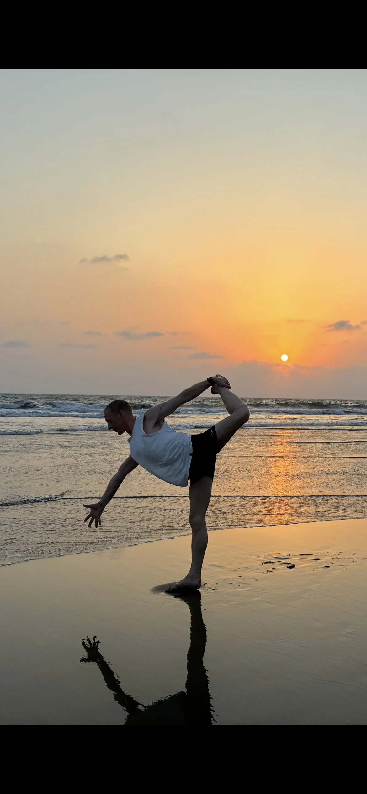 Portrait of a man outdoors with a blue sky and trees, wearing a dark jacket and a gray scarf.
