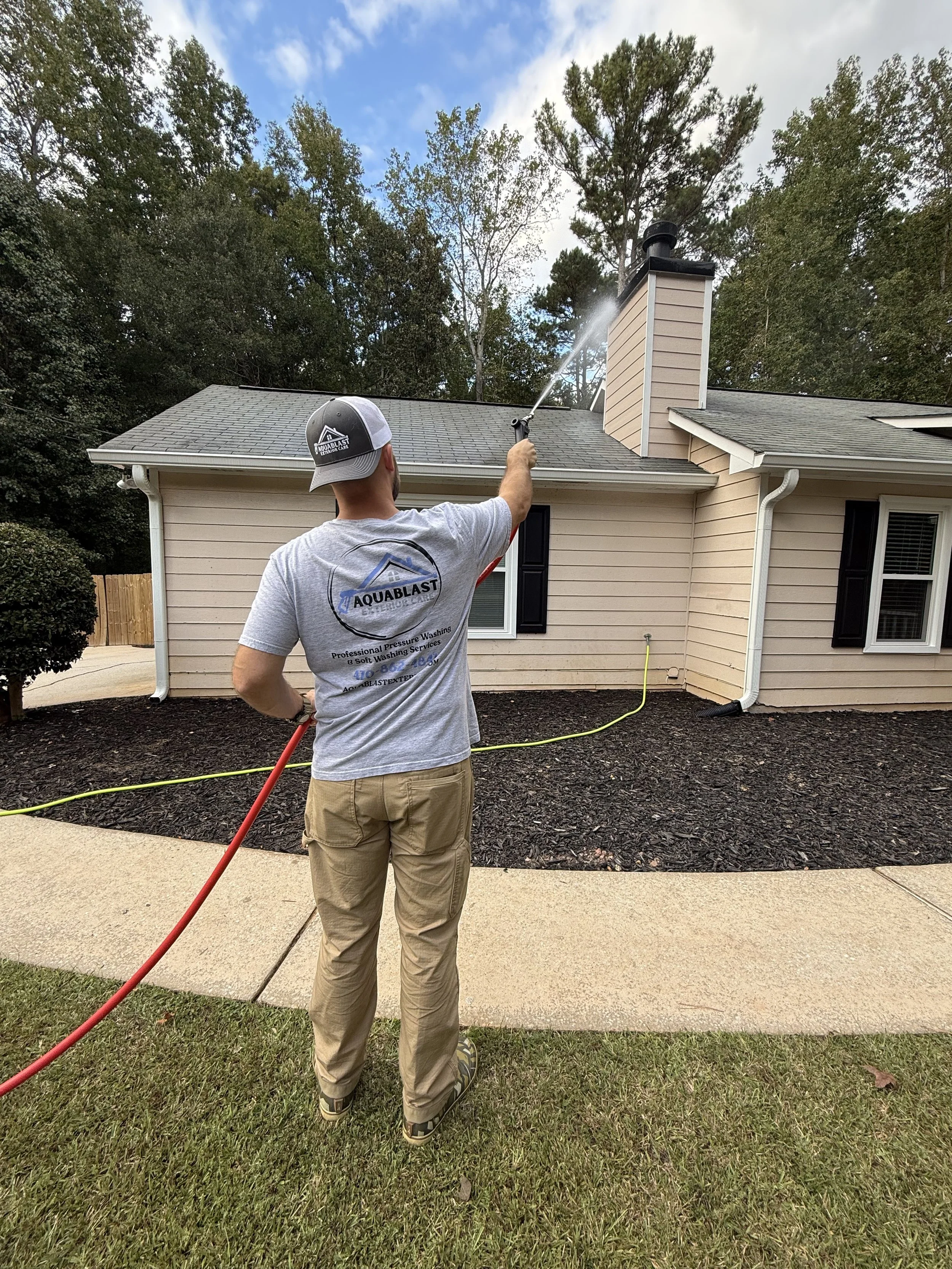 A person power washing the roof of a house.