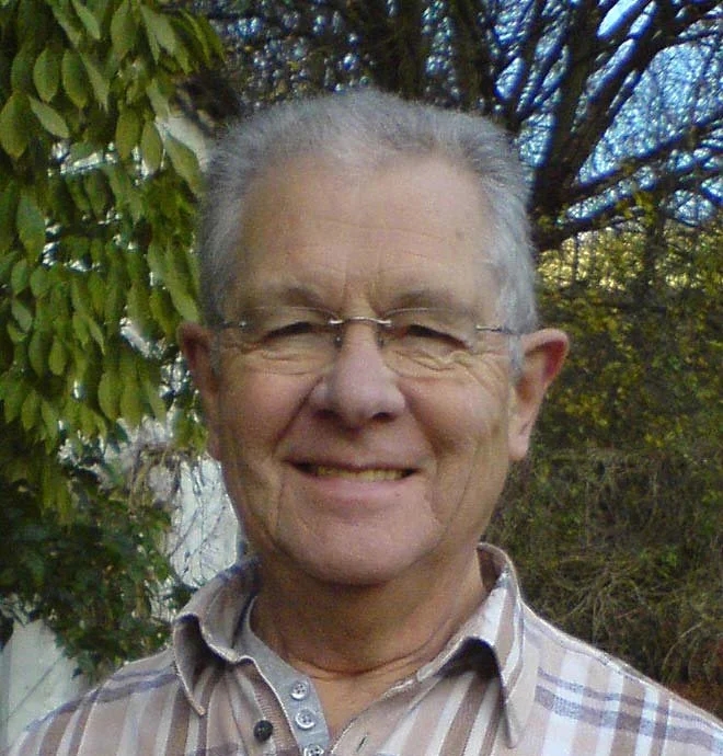 Portrait of Stephen Darbishire smiling outdoors with trees and foliage in the background.