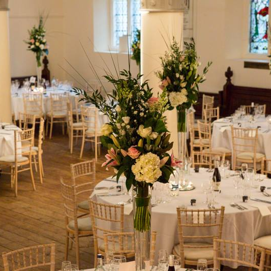 Elegant banquet hall decorated with floral arrangements and set tables for a formal event.