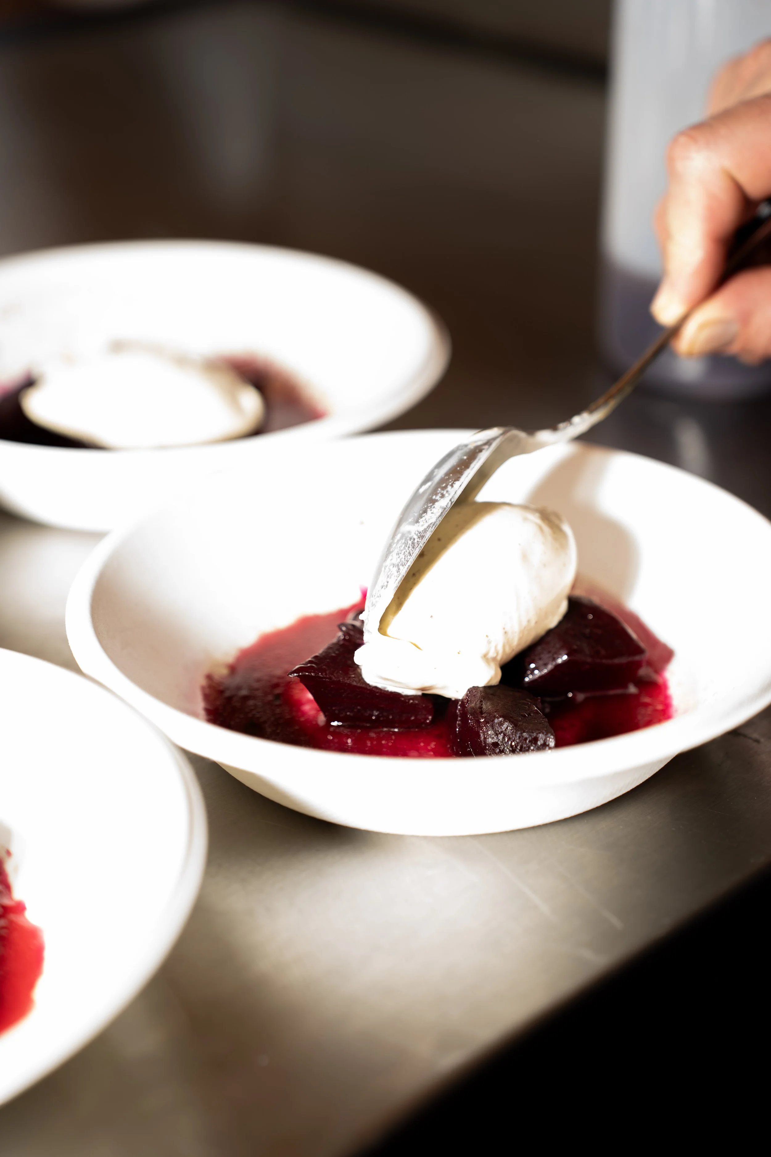 Een dessert met rood bery prae en een bol romige ijs in een witte kom, versierd met een stukje bevroren fruit.