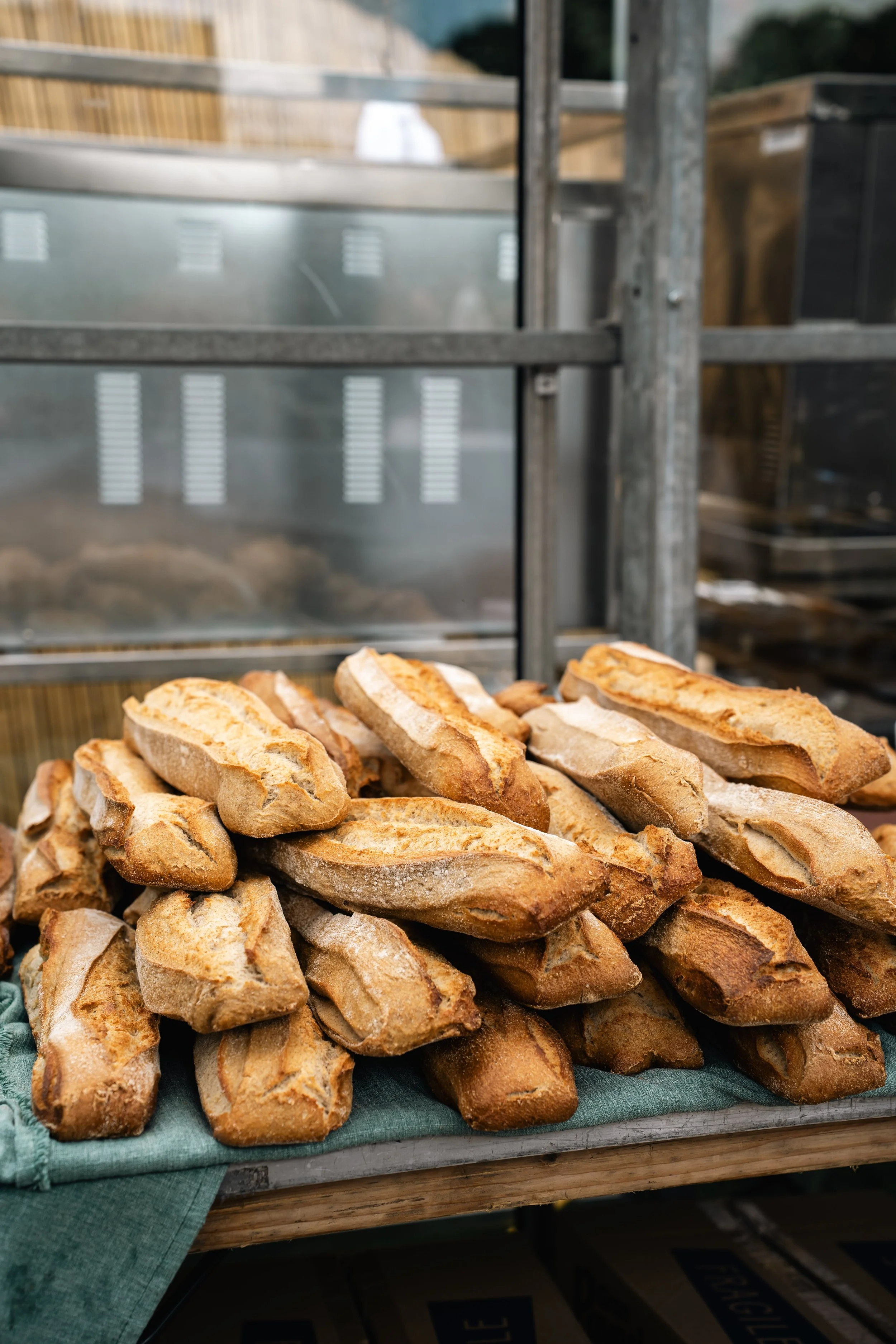 Hoezen met gestylde baguettes op een tafel met groene doek, bakkerijwinkel achtergrond.