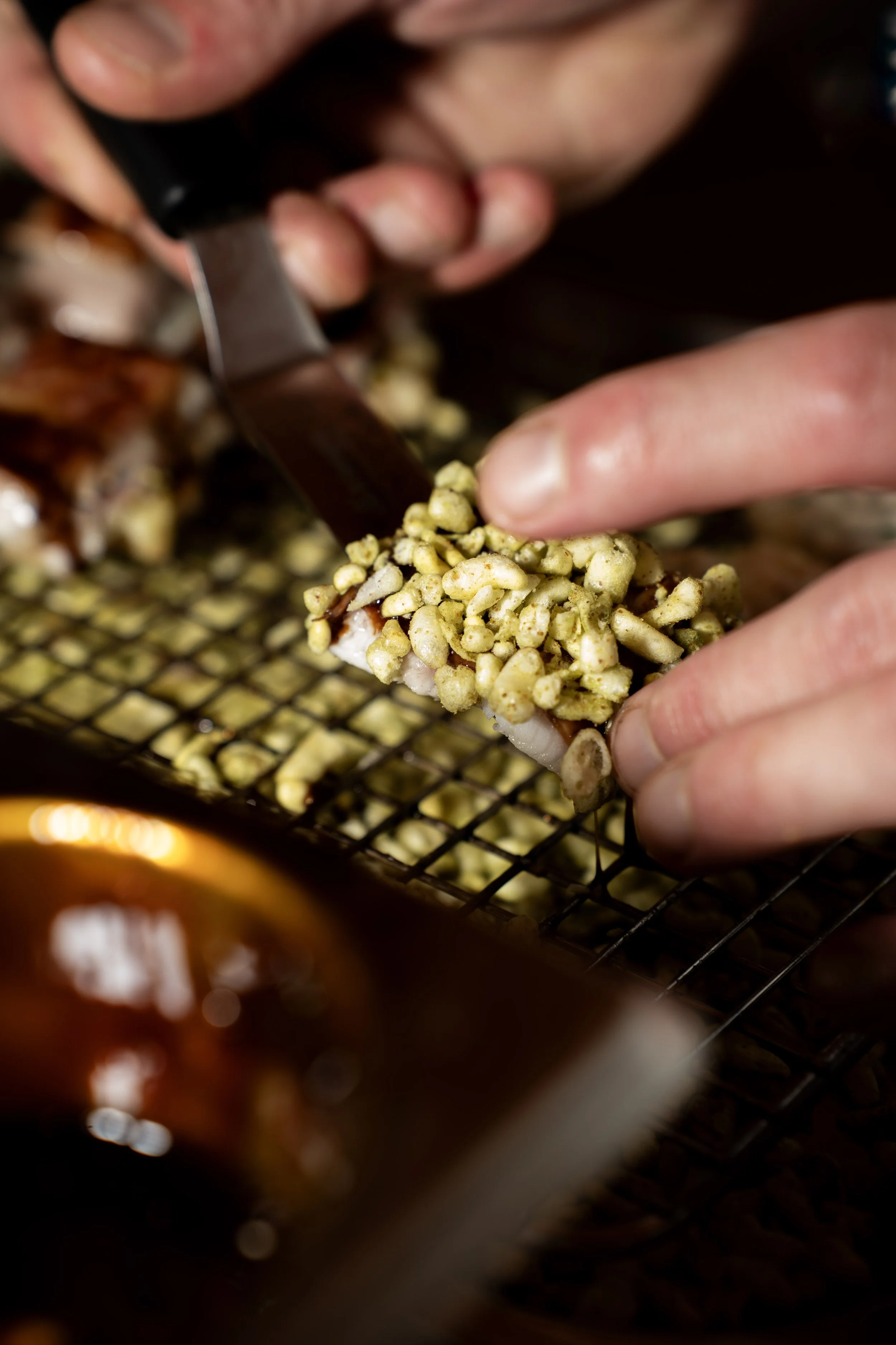 Mensen maken sushi met stukjes vis en gedroogde bamboeschijf, versierd met wasabi en gember, in een restaurantkeuken.