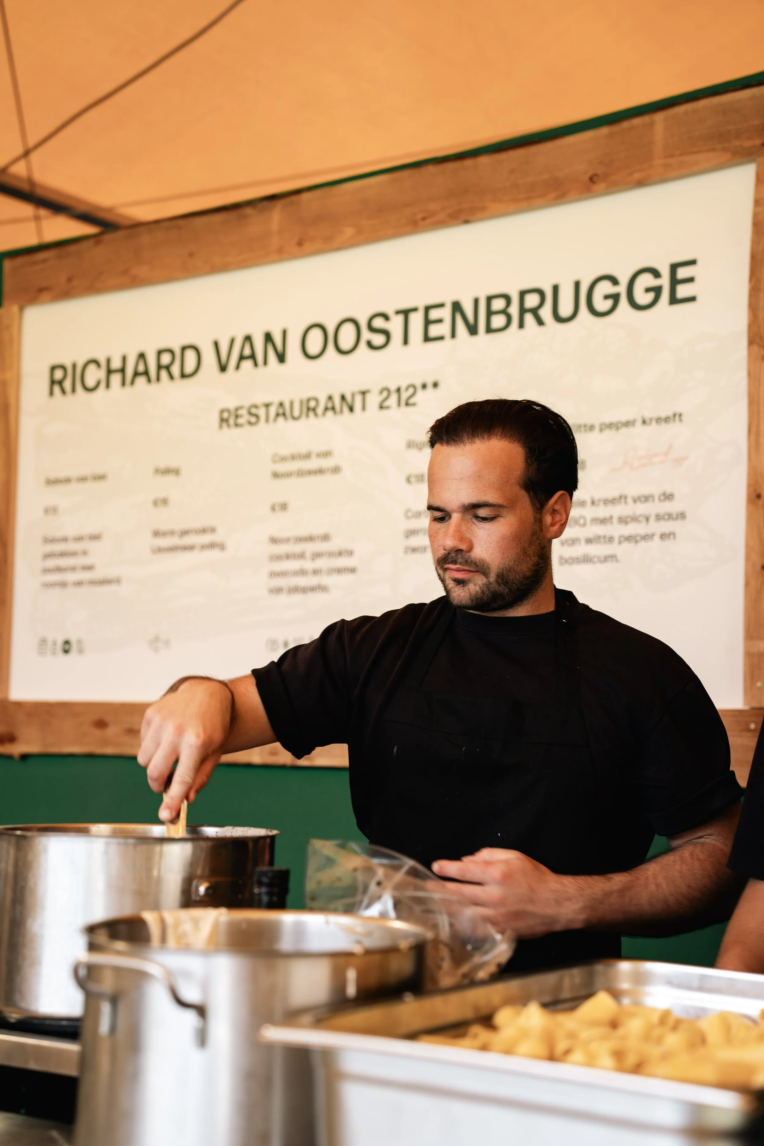 Man kookt of bereidt voedsel in een keuken met een menu bord op de achtergrond.