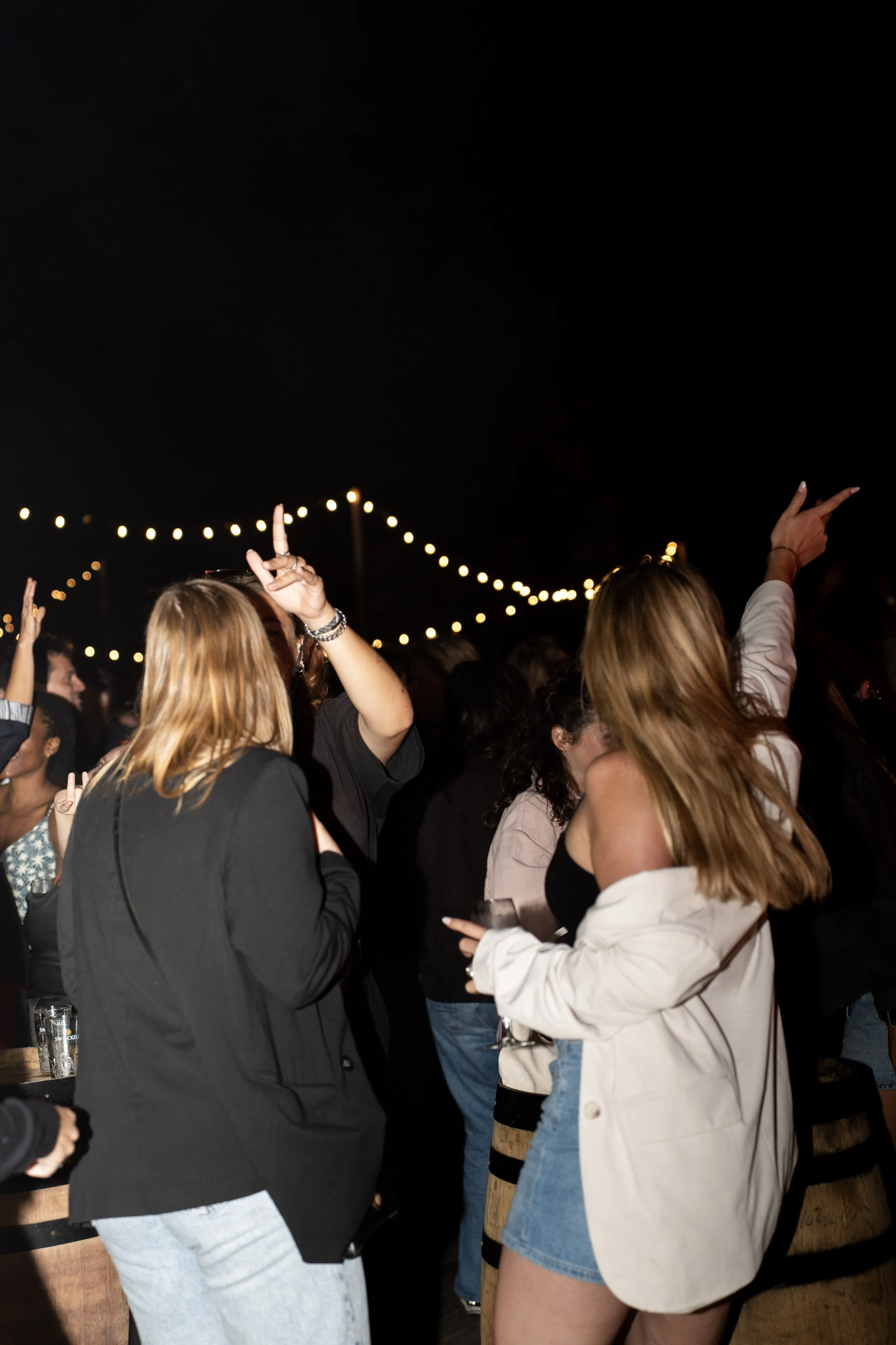 Mensen die dansen en plezier maken op een feest of evenement met string verlichting boven hen.