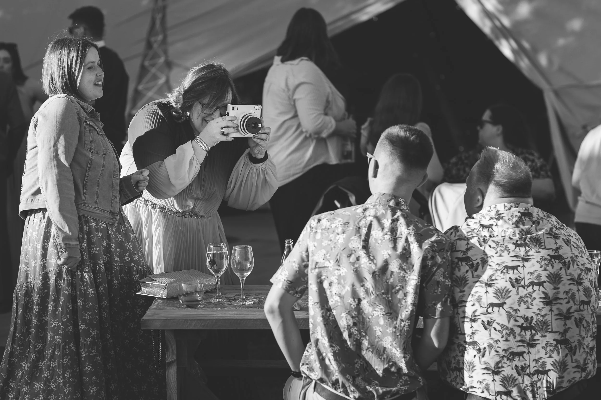 A wedding guest takes photos of other guests using a polaroid camera