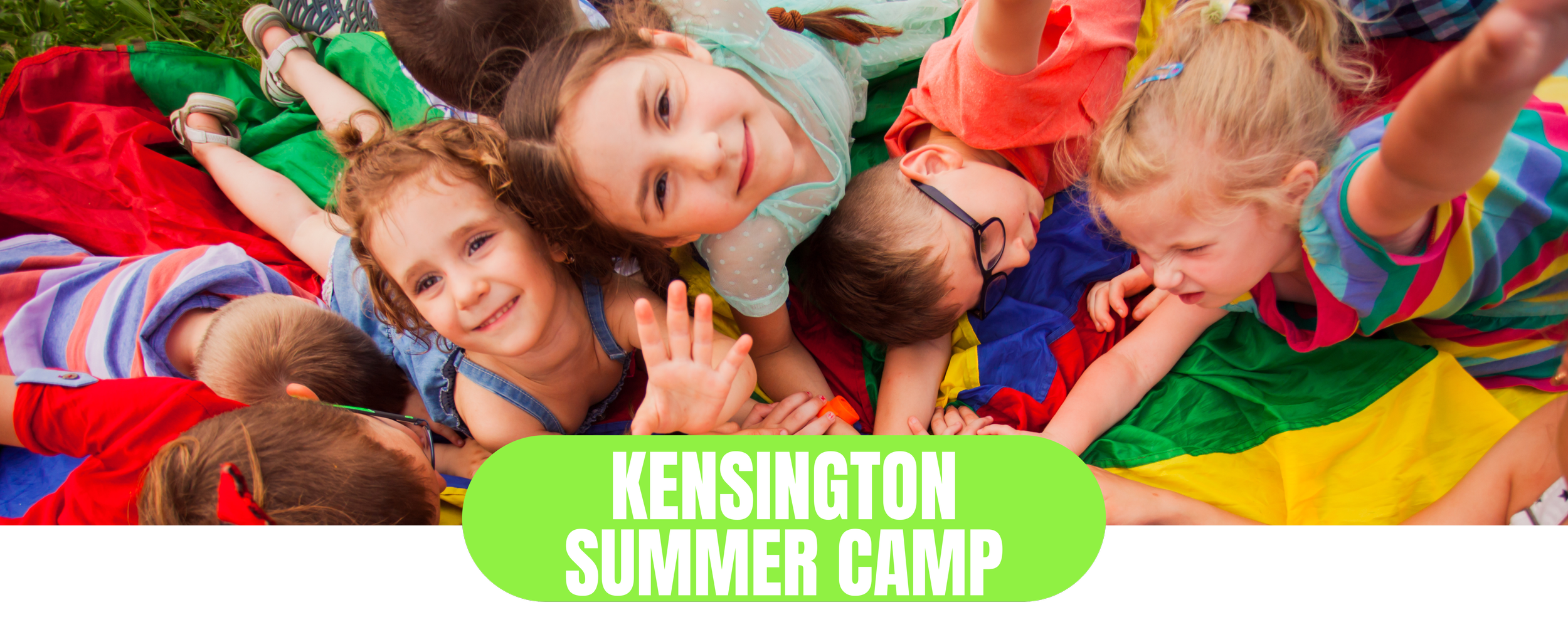 Children playing and smiling during Kensington Summer Camp, lying on a colorful parachute outdoors.