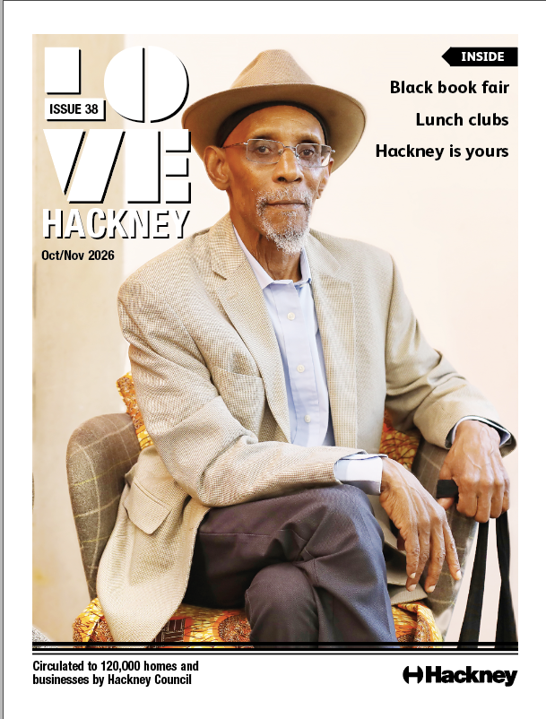 Poet Linton Kwesi Johnson sits on a hair with a hat. Front cover of Love Hackney, issue 38, October / November 2026