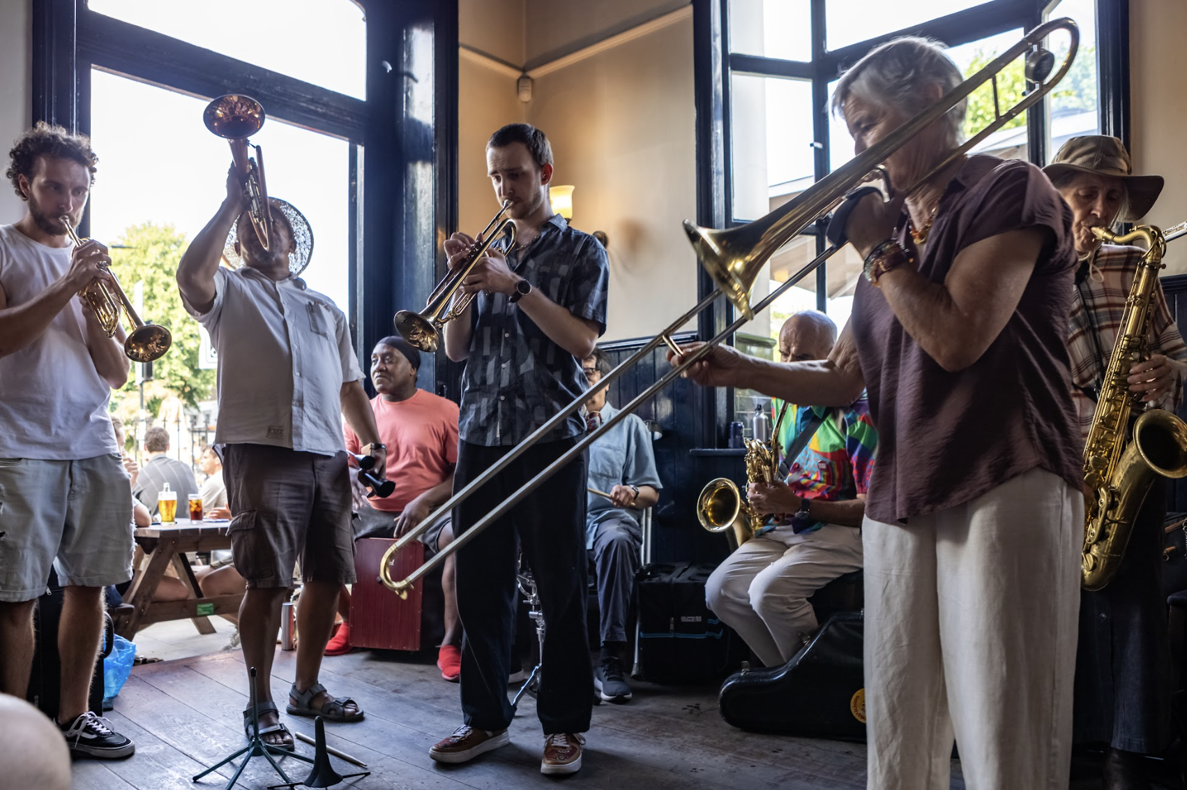 a picture of 8 musicians play musical brass instruments, they are all male of different ages