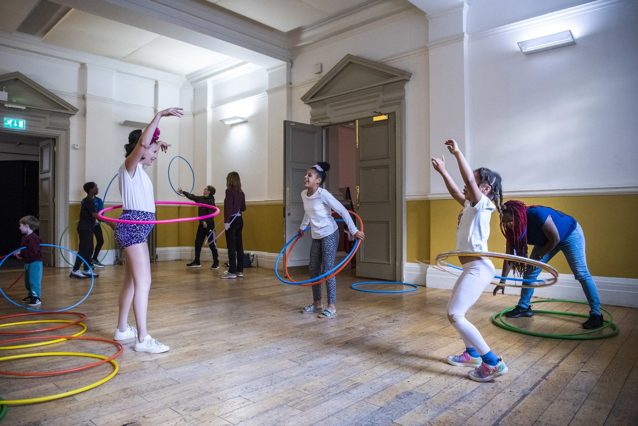 Children play with hula hoops in a large space at Shoreditch Town Hall