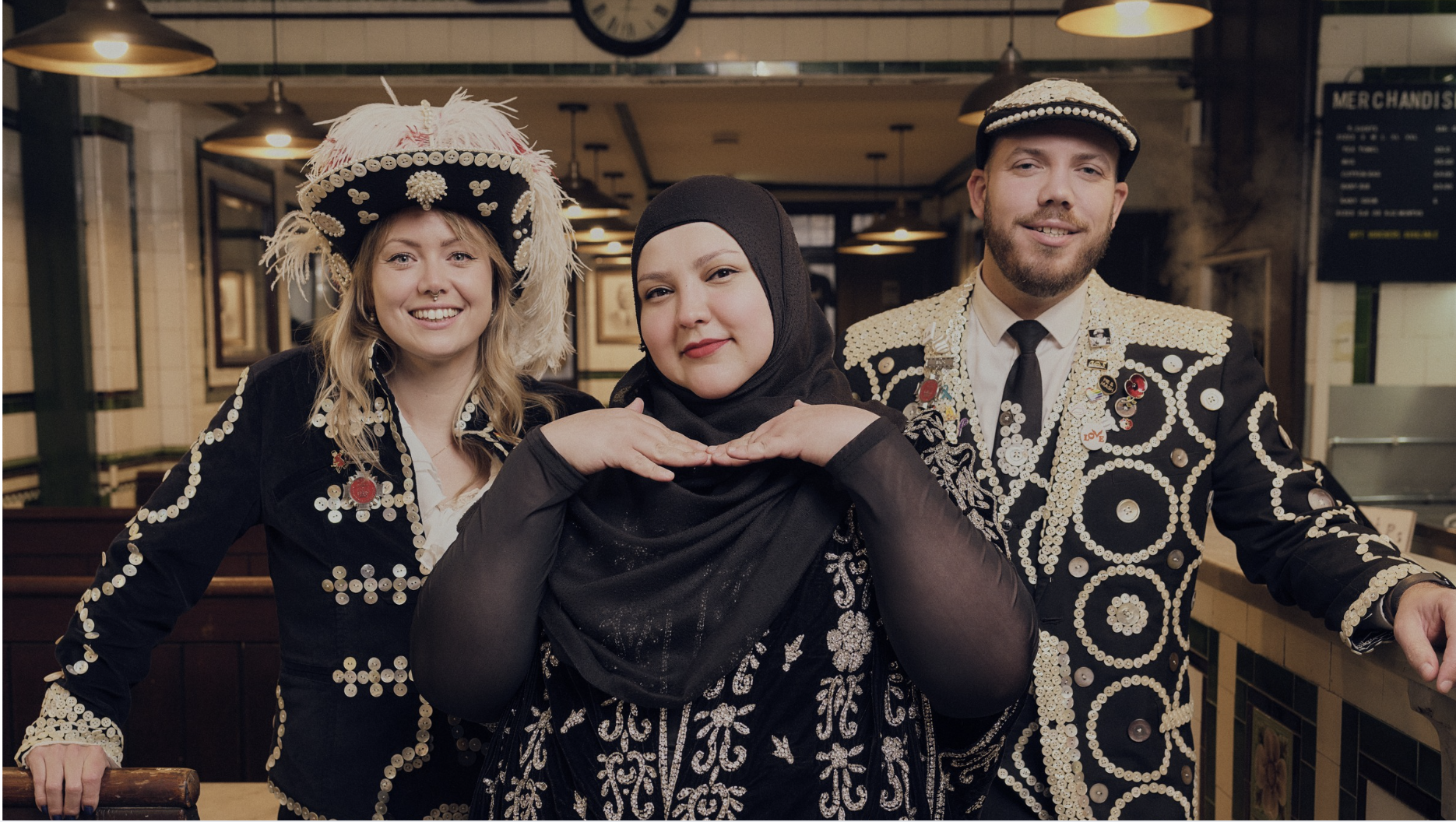 Fatiha, dressed in her hijab, is flanked by a pearly king and queen