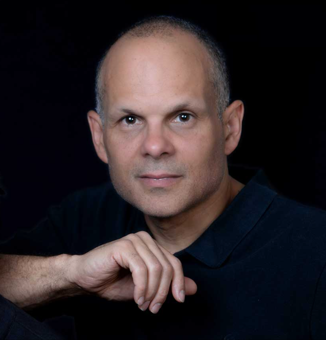 Editor Steve Pope posing for a professional headshot against a Black background.