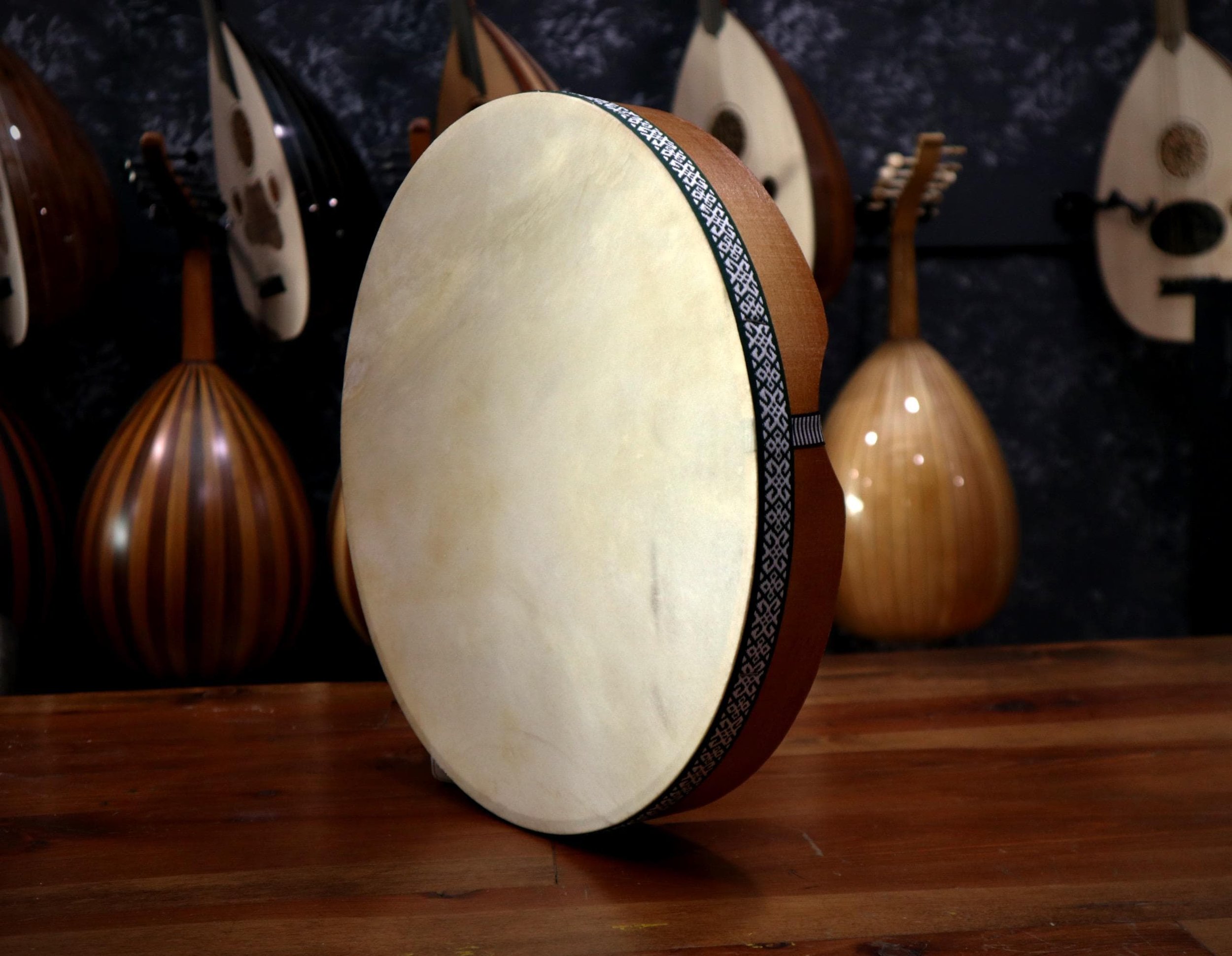 An Erbane drum stands upright on a table infront ogf other stringed and traditional instruments