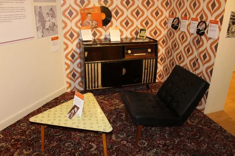 An old room decorated in 1970s style with orange patterned wallpaper with a record player