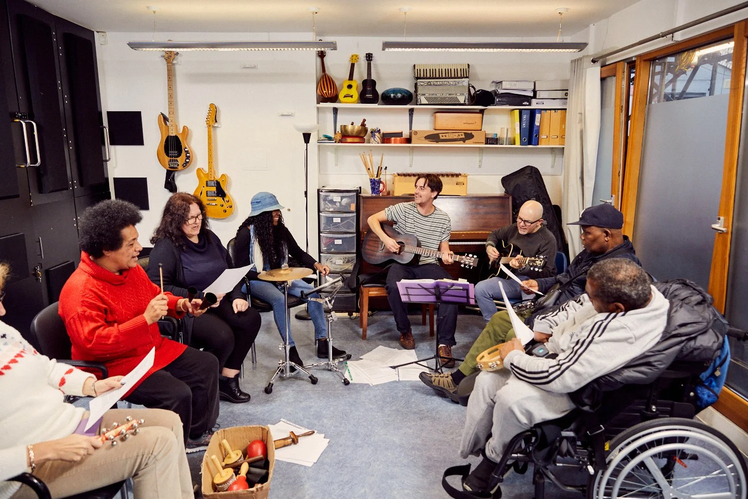 A group of Headway members sit in a semi-circle during a music workshop