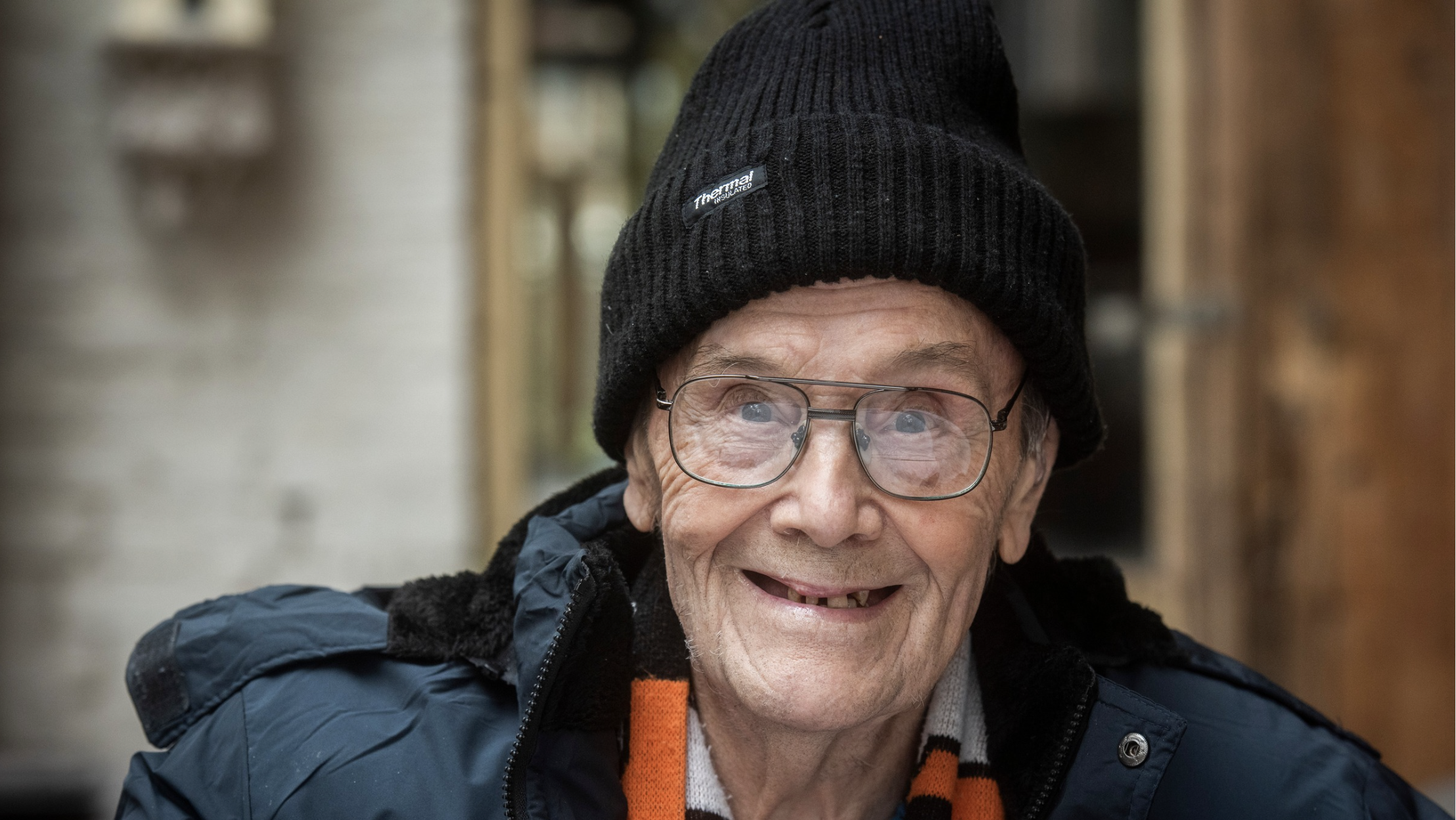 an older man wearing glasses and a wool hat