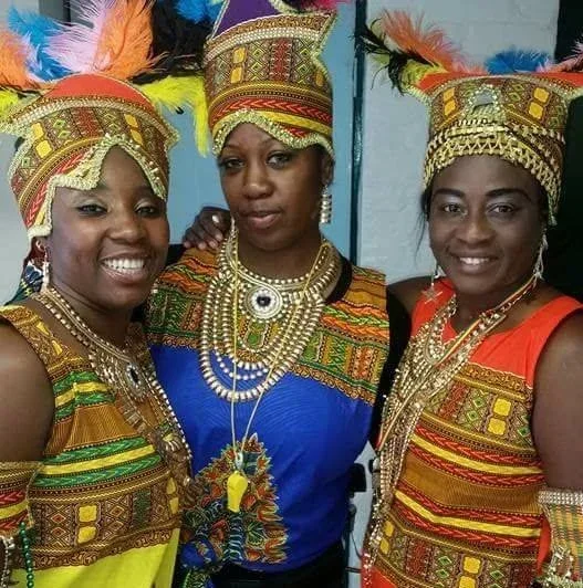 Three women dressed in colourful, carnival-style headresses and dresses