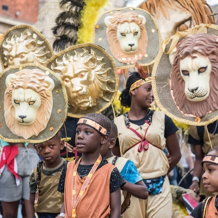 Children walk in a parade holding decorative lion heads