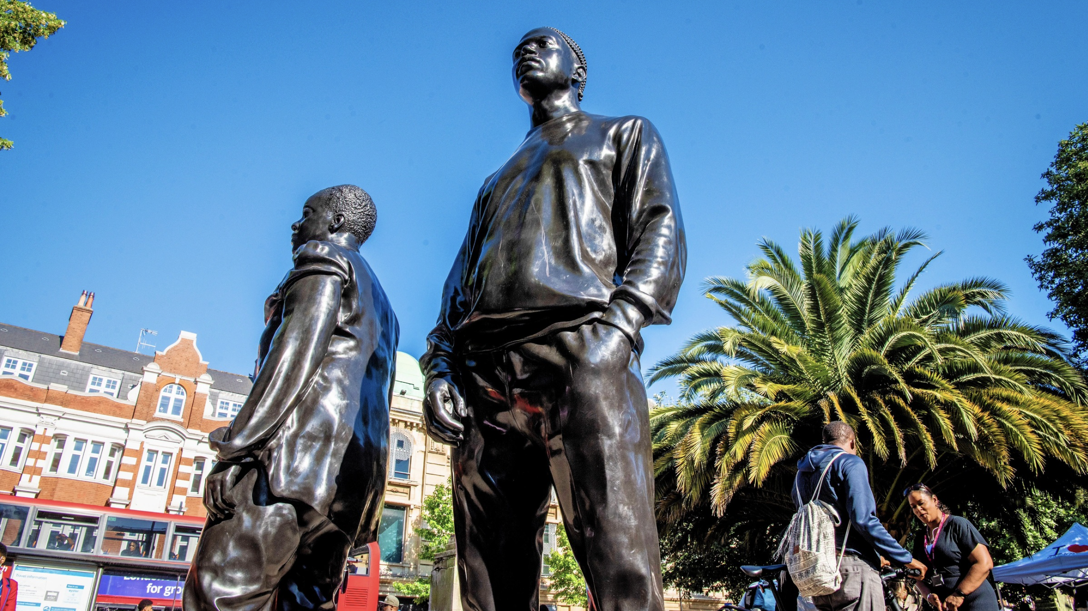 Two large sculptures of people against a blue sky