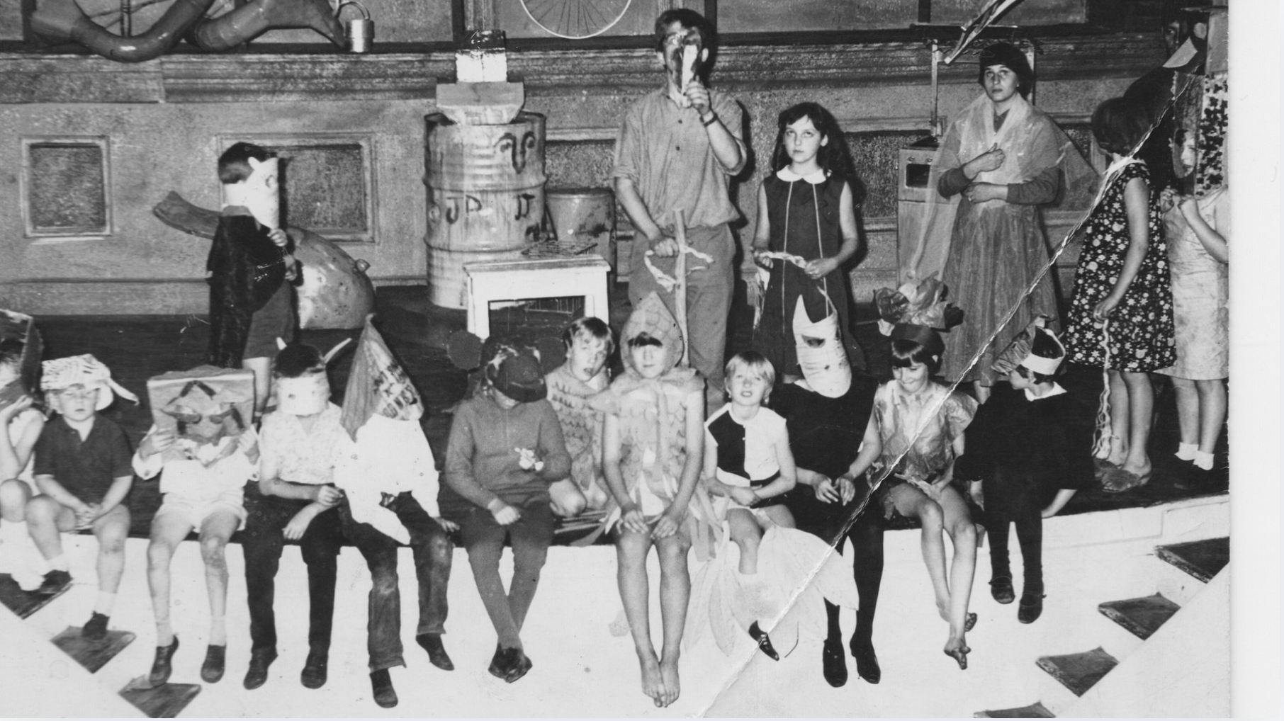 a black and white photo of children sat on a stage