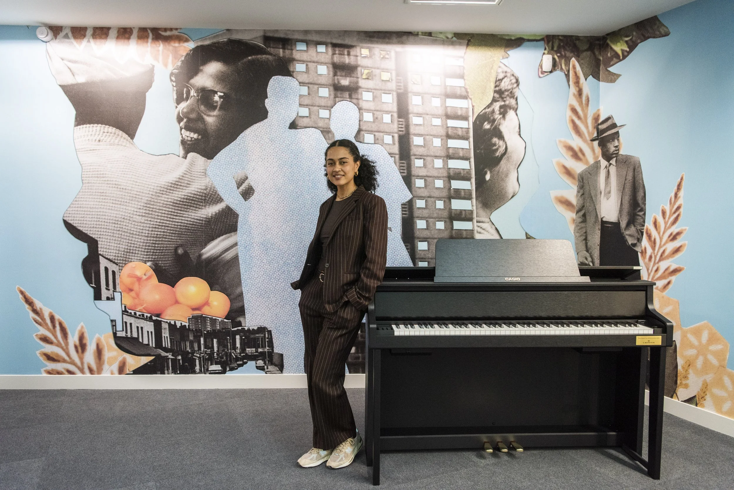 jazz grant artist in front of her mural leaning next to a piano