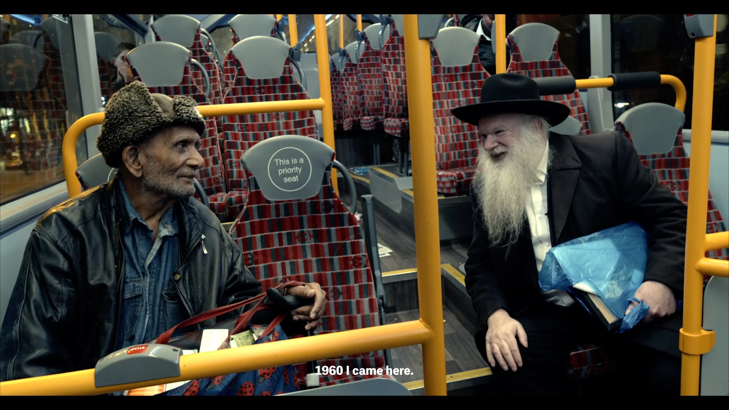two men in hats talk to each other on an empty bus