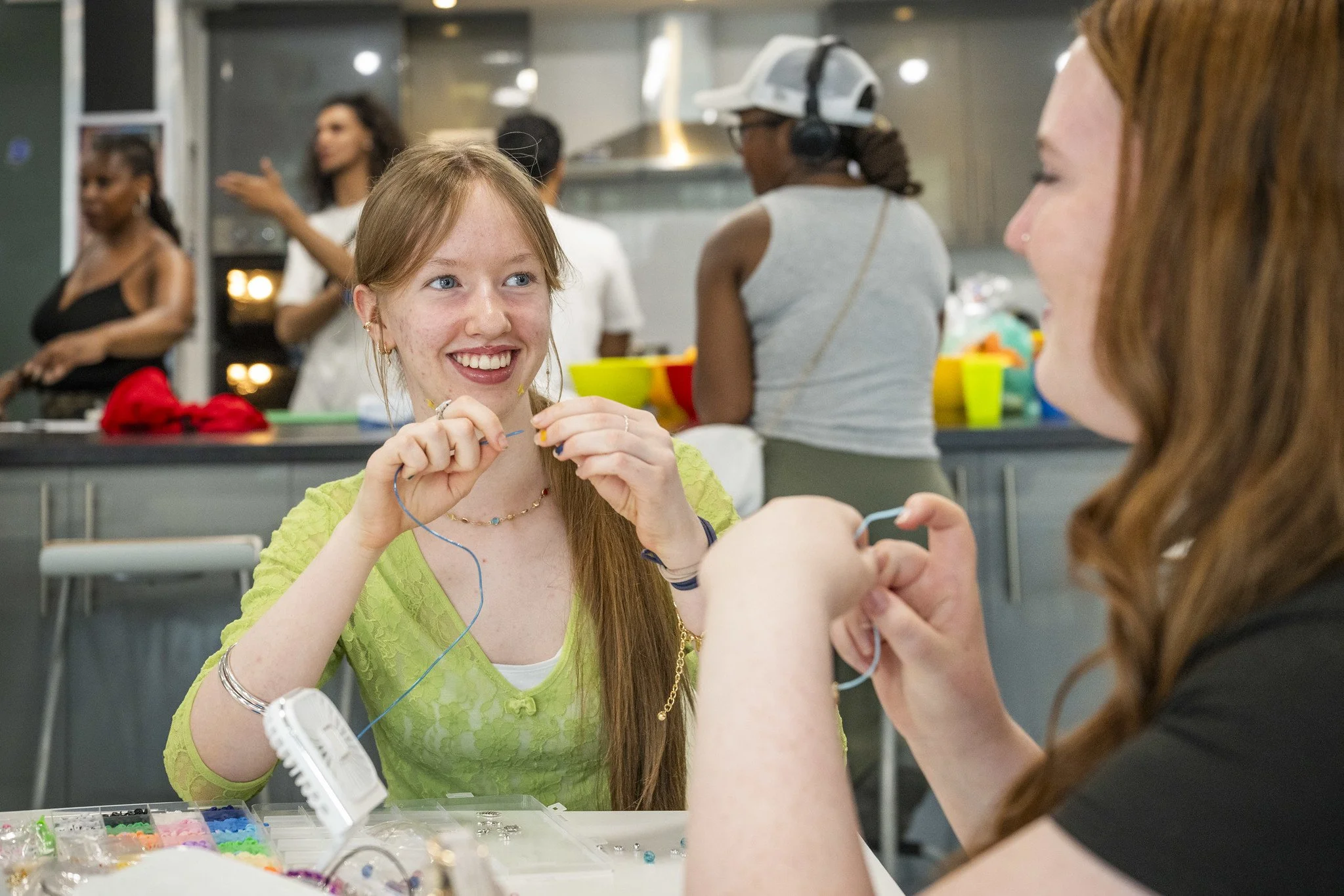 Two teenage girls, who appear to be friends are engaged in bracelet making