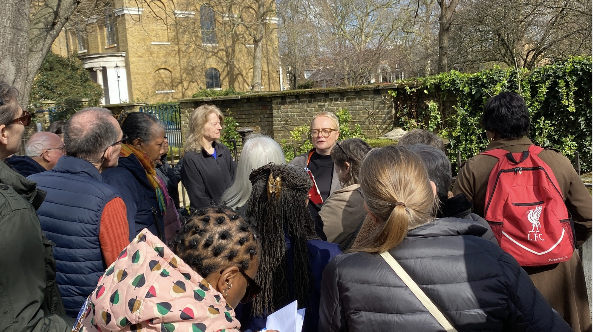 A group of people stand outside listening to a guide