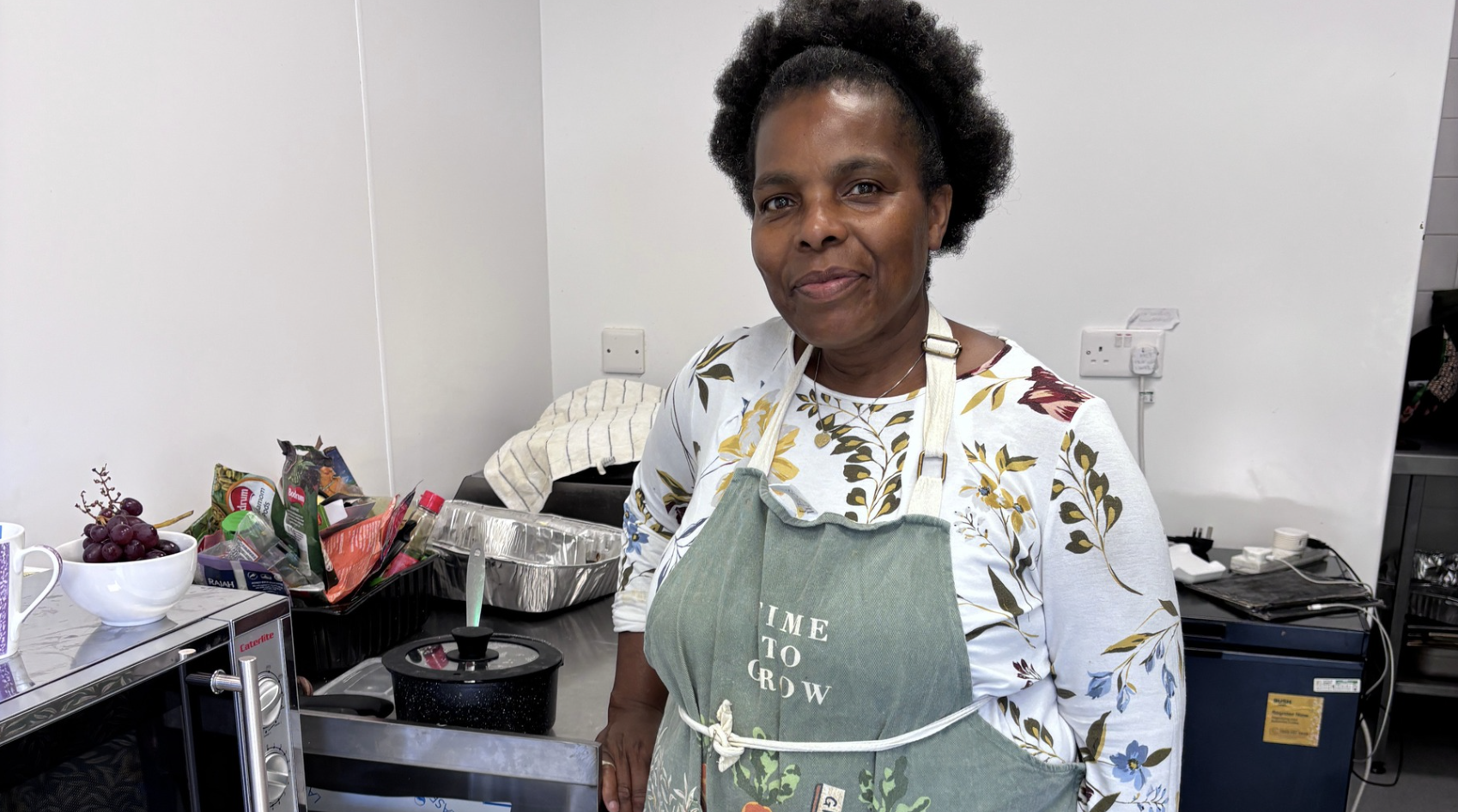 a woman wears an apron that says 'time to grow' in a kitchen