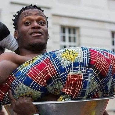 A man with tightly knotted hair with an African-style tapestry