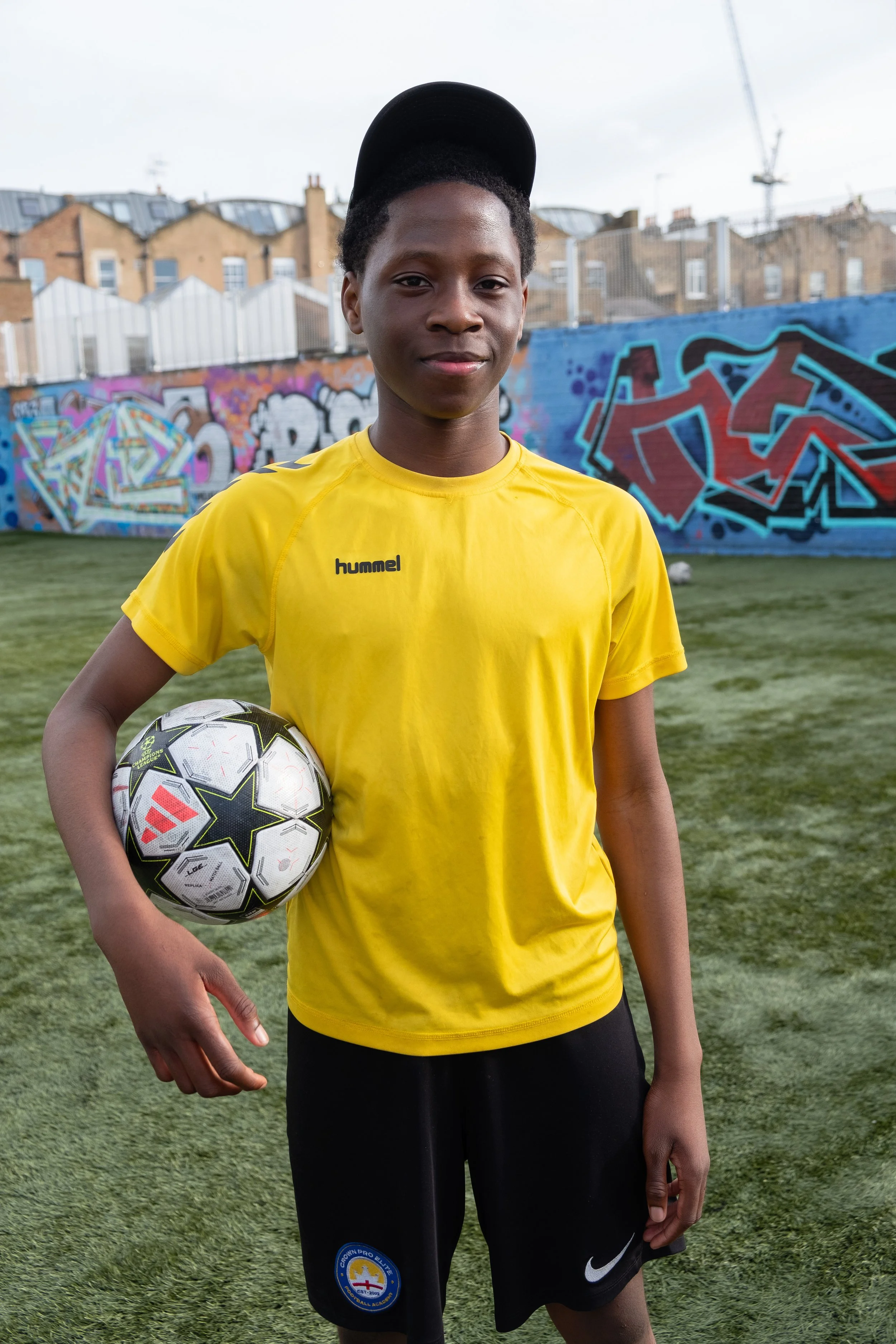 A boy in a yellow t-shirt holds a football