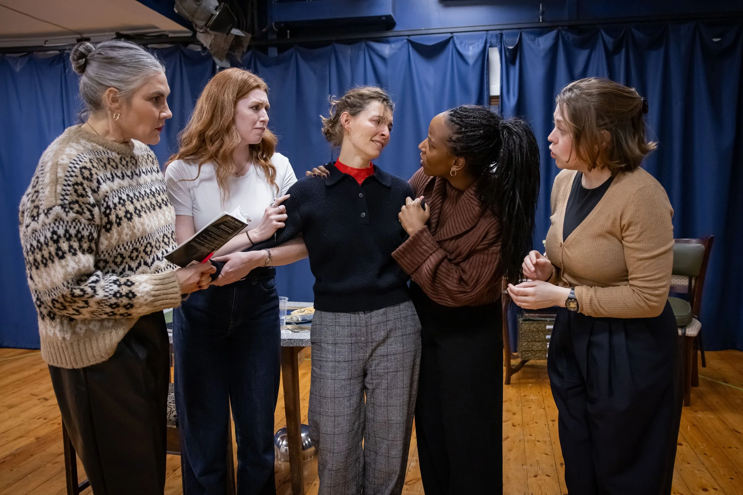 Image of 5 women from various backgrounds reading from scripts in a rehearsal room