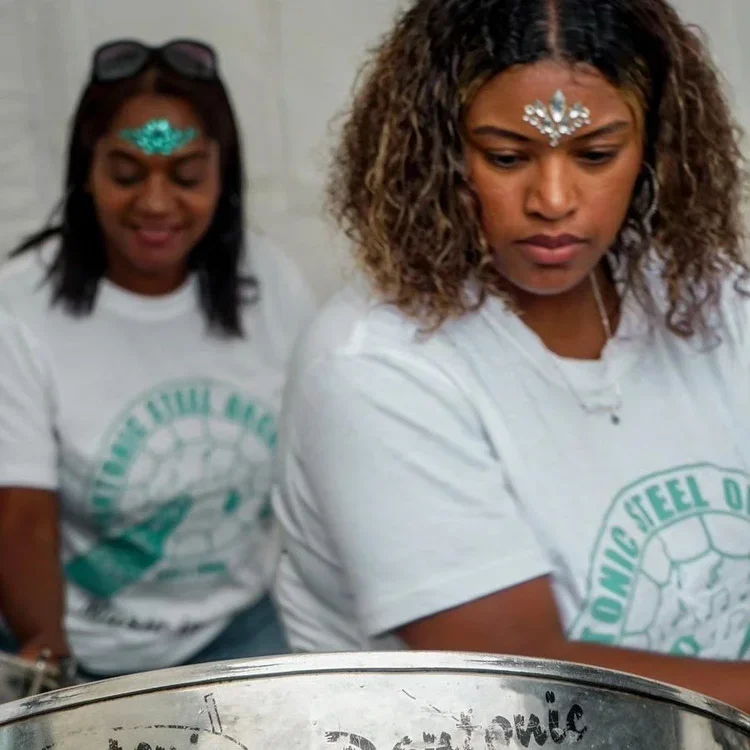 Two women wearing t shirts with the Pantonic Steel logo. They wear jewel style accessories on their foreheads
