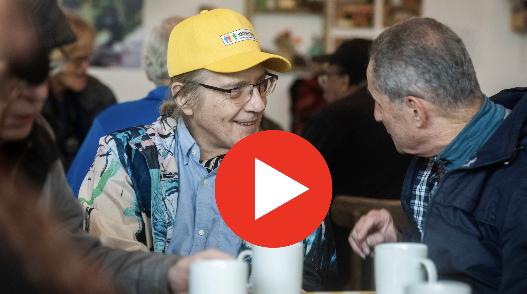 Two men, one wearong a yellow cap that says 'Hackney Dudes' , chat to each other