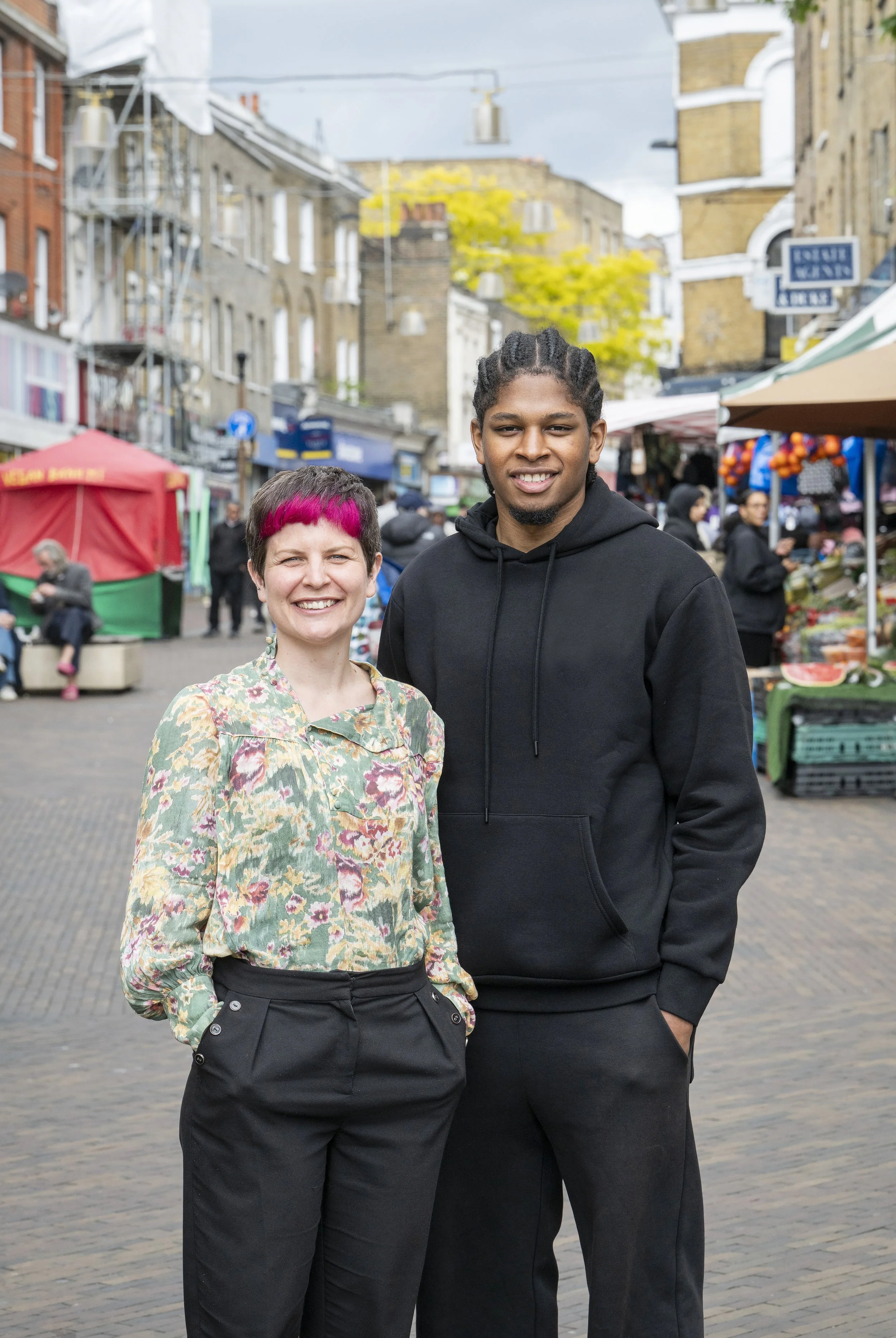 A man and woman stand side by side outside a market