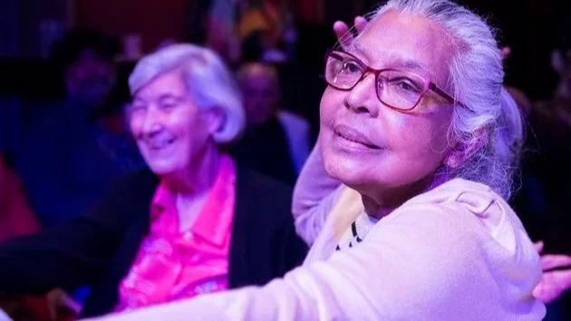 Two women enjoy a performance at a Diwali event