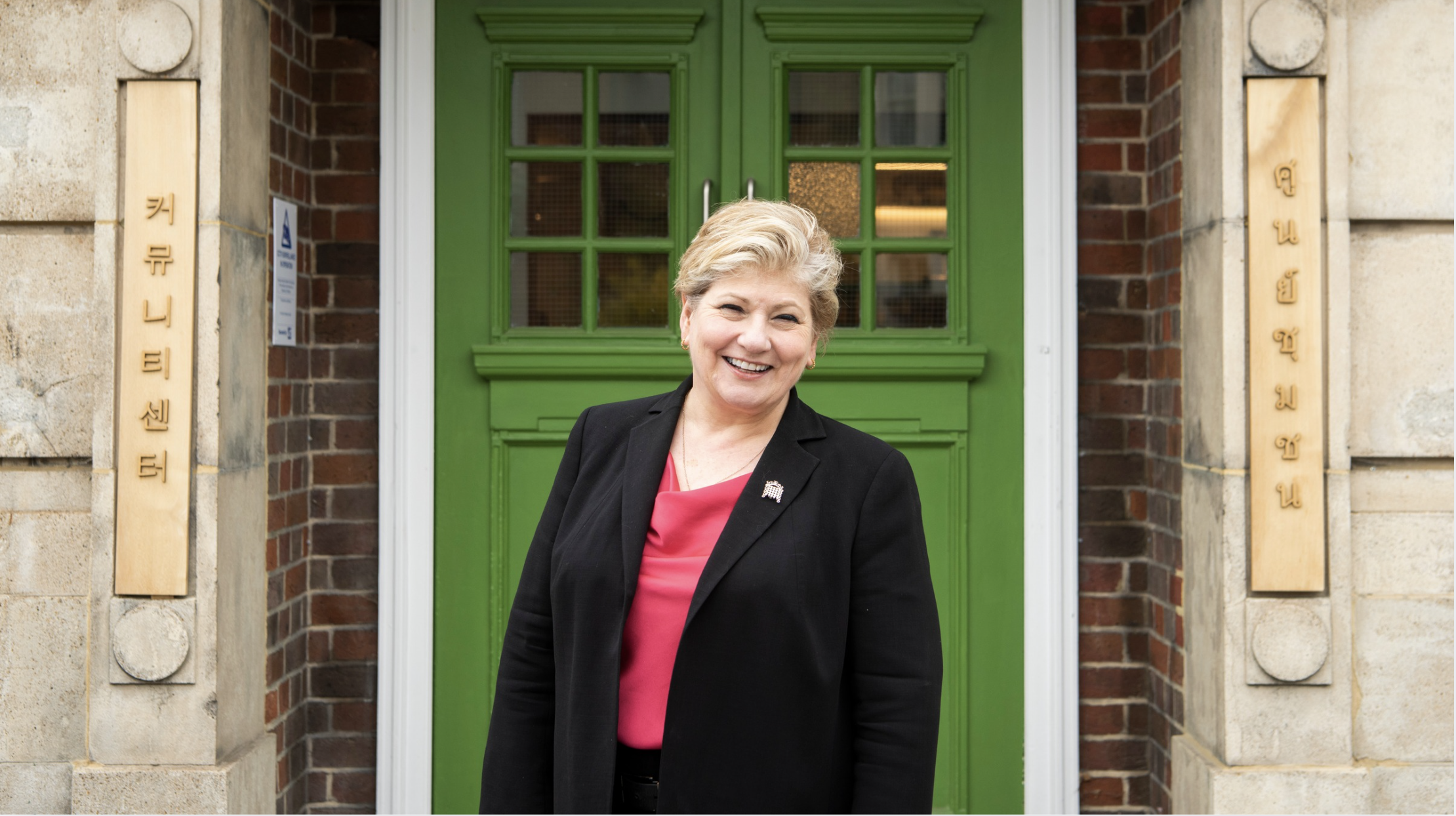 A woman stands in front of a green door smiling