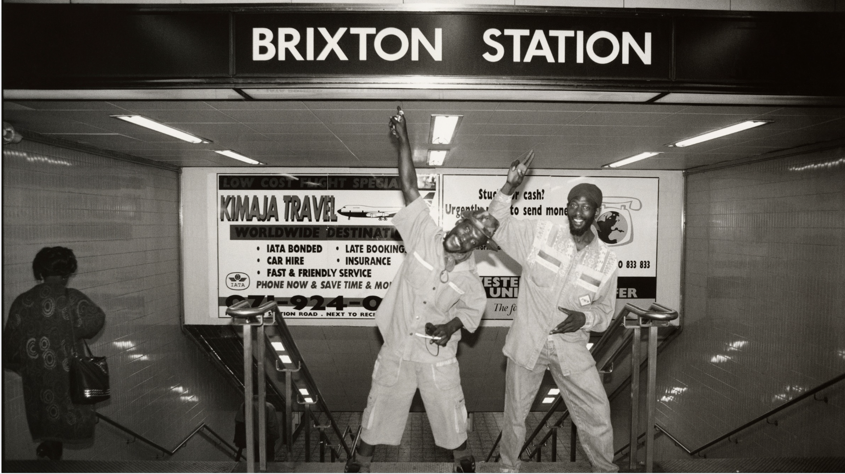 2 people dance in front of brixton tube sign