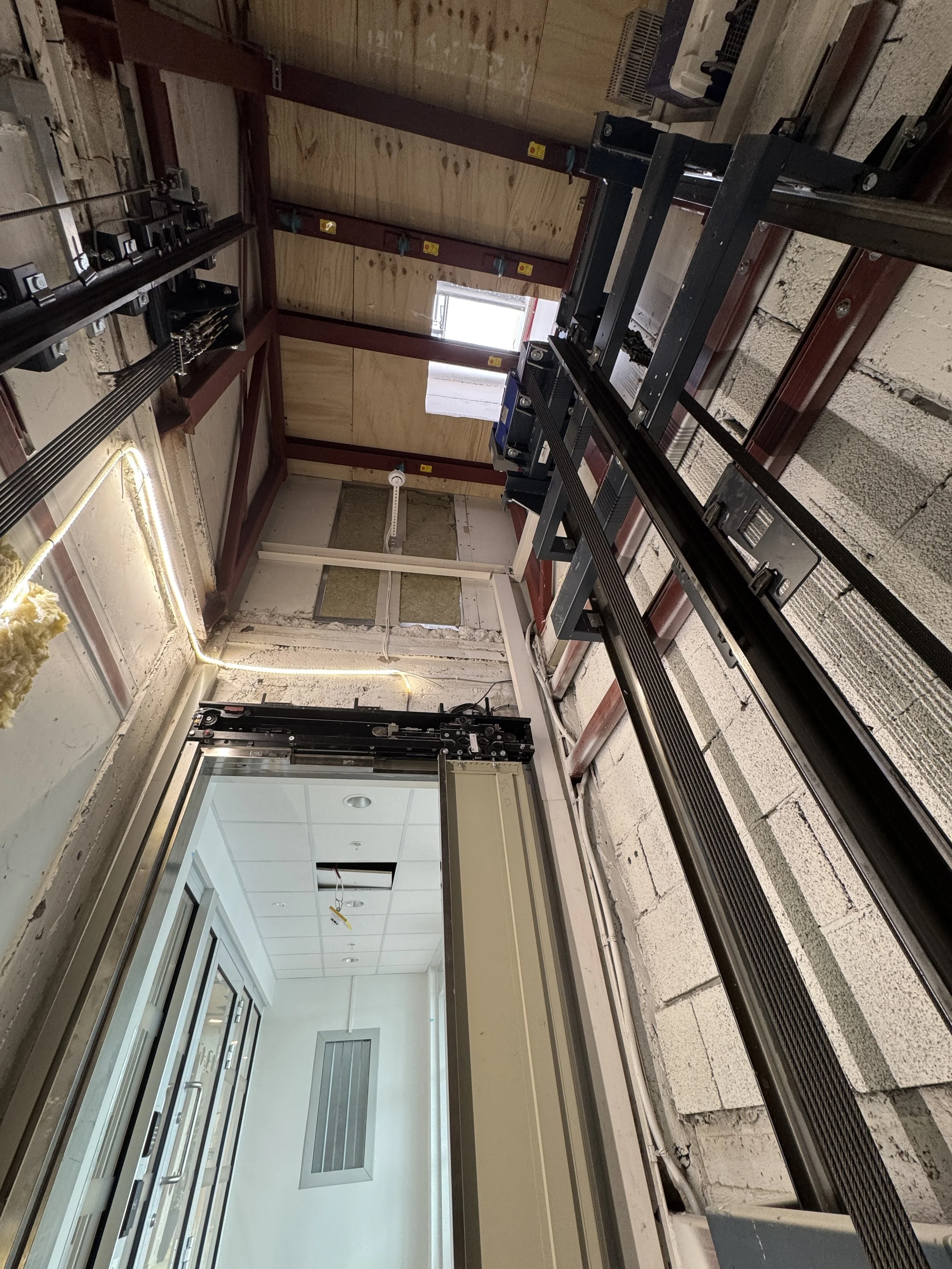 Innendørs bygging med metallrammer, skinner og noen vinduer under konstruksjon eller oppussing.