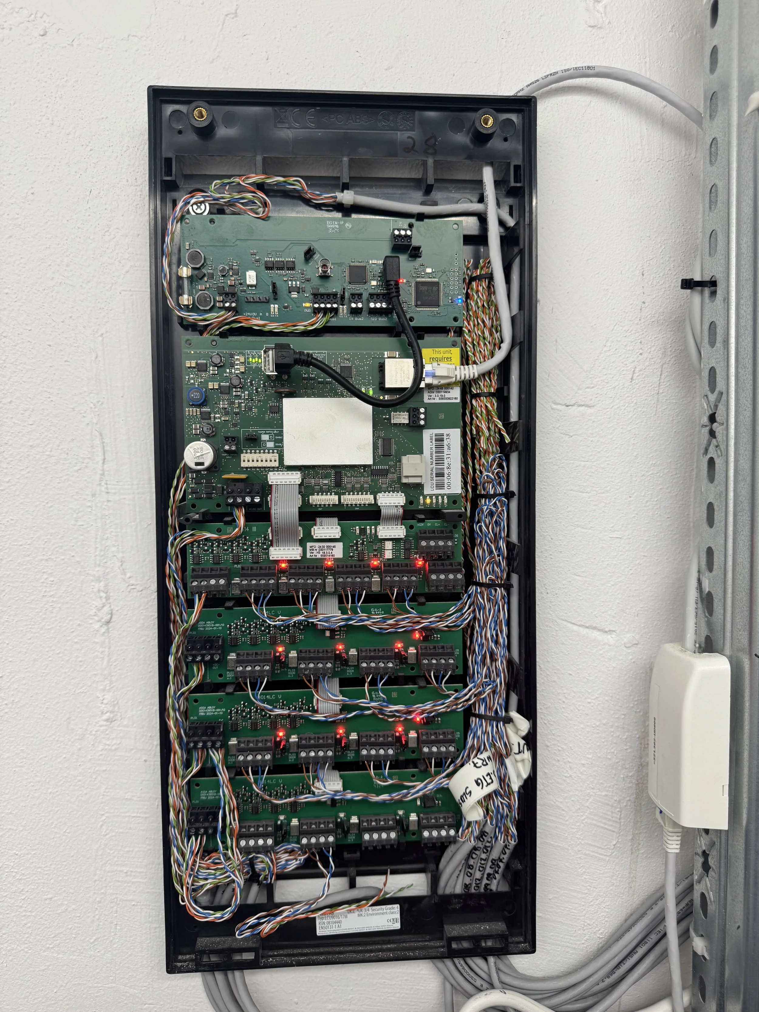 Innfelte elektriske styringer og kabler i en kontrollboks montert på vegg.