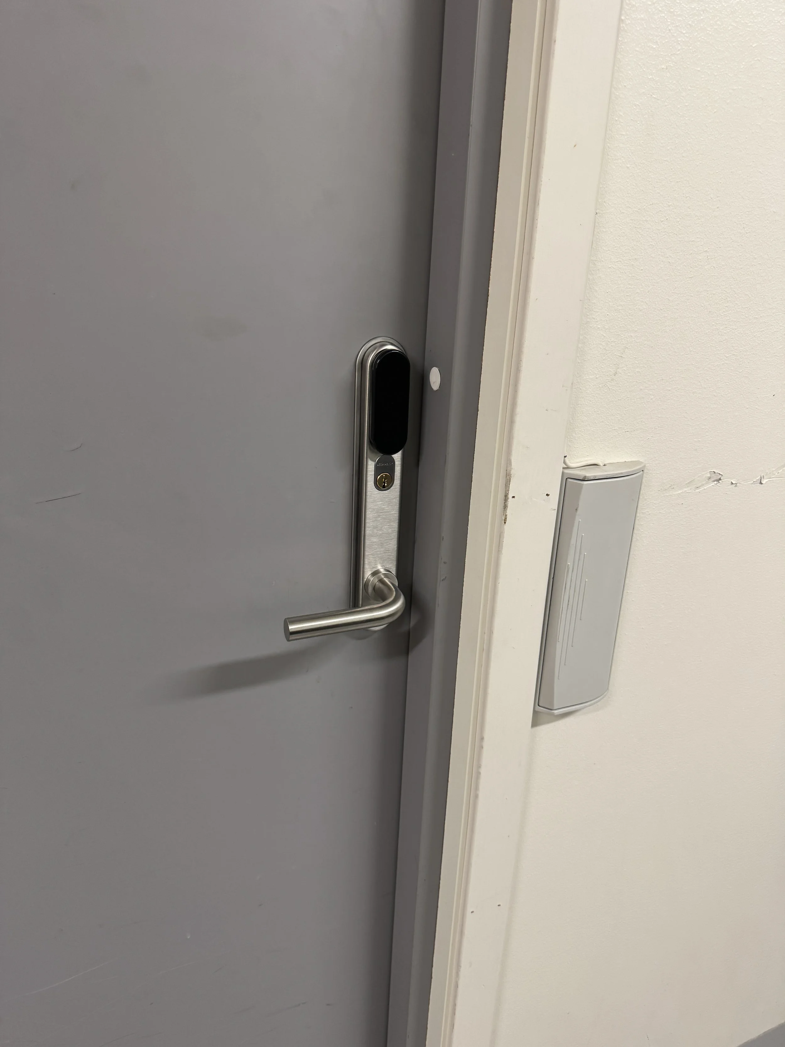 Låst dør med elektronisk adgangsleser ved siden av en lys vegg.