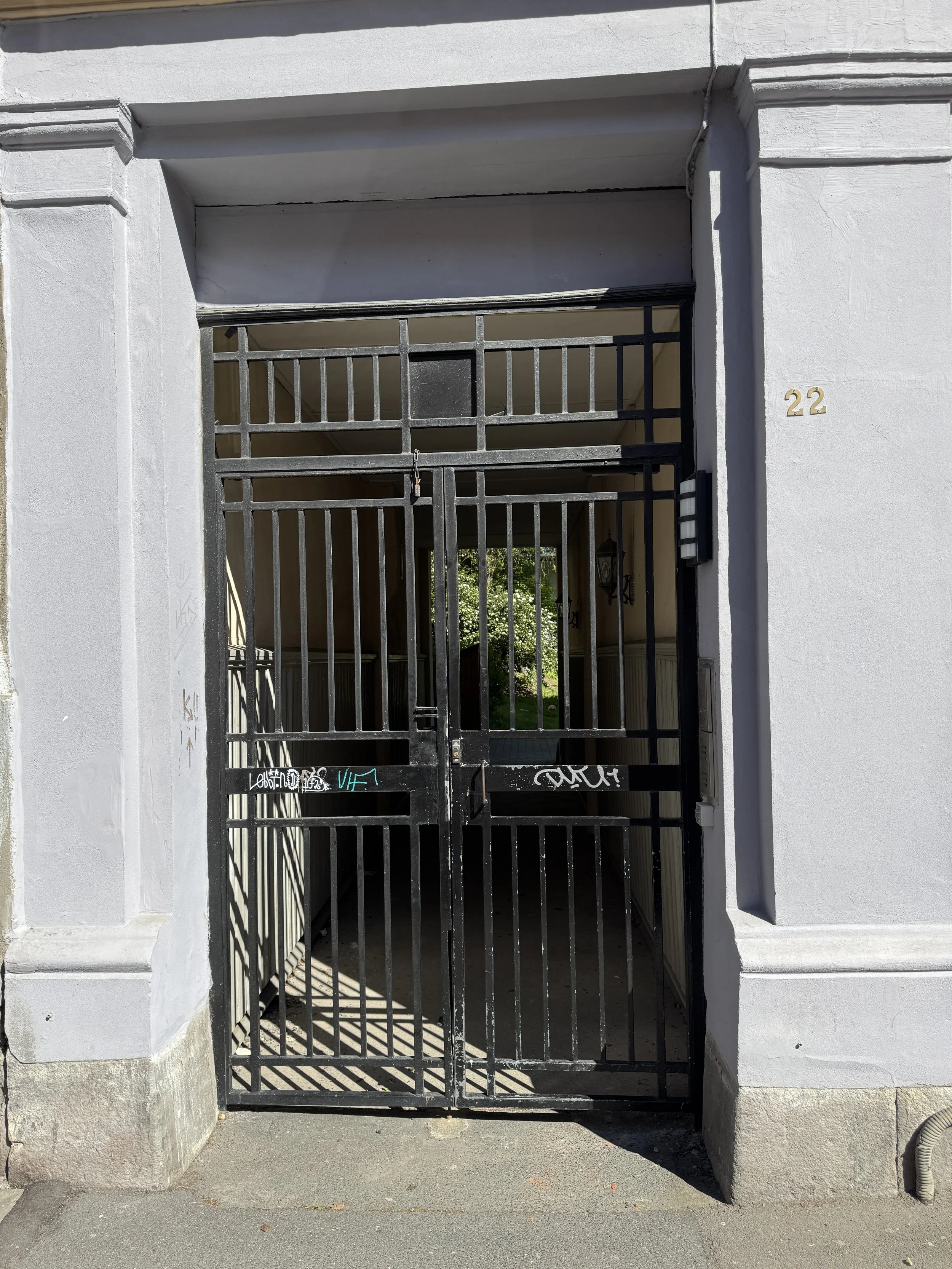 Gitterport ved inngangsparti til en bygning med leiligheter, nummer 22 på veggen.