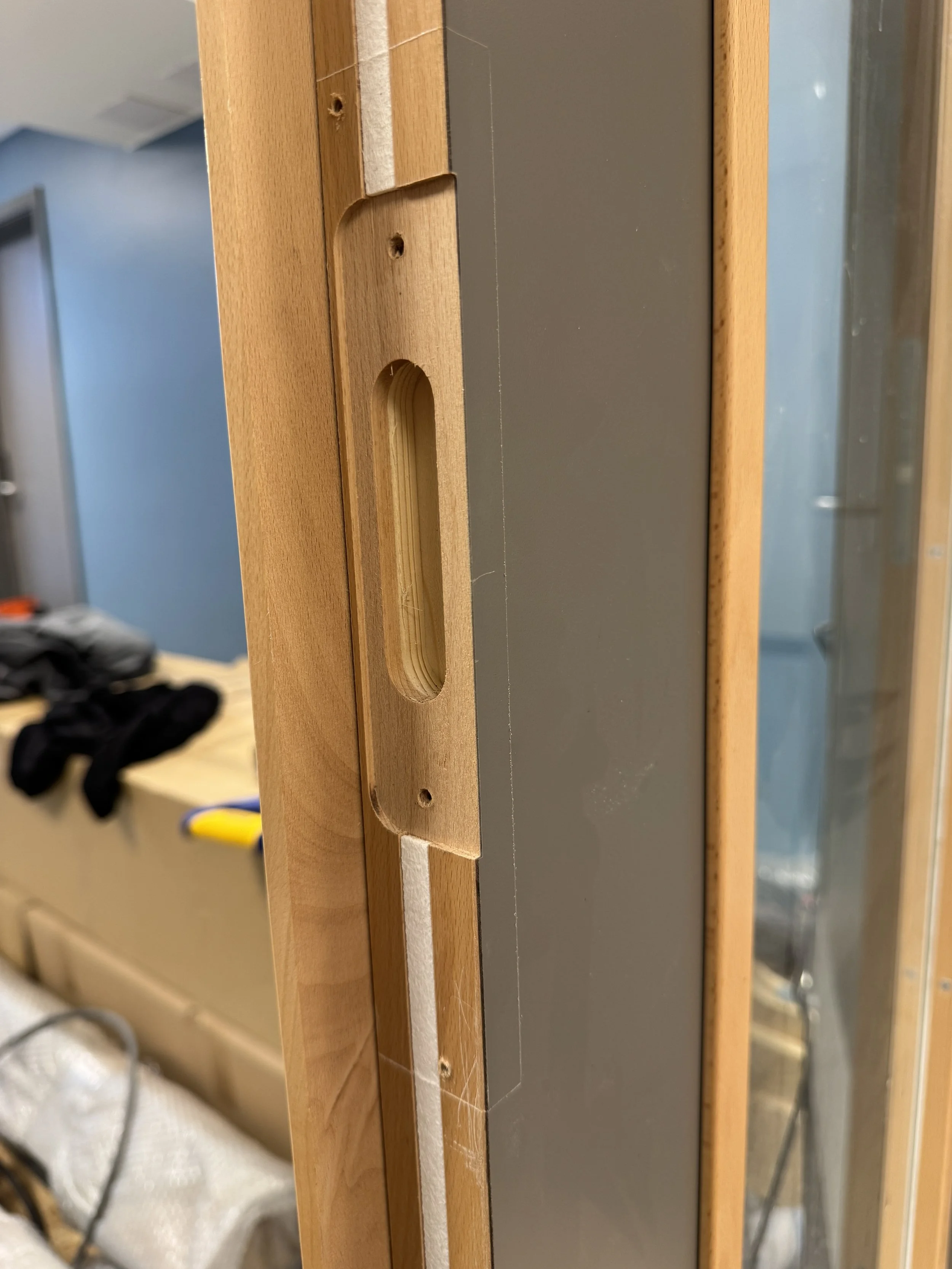 Nærbilde av en del av en treramme med en utstøtingsskinne eller spor, sannsynligvis for glass i en dør eller et vindu under konstruksjon.