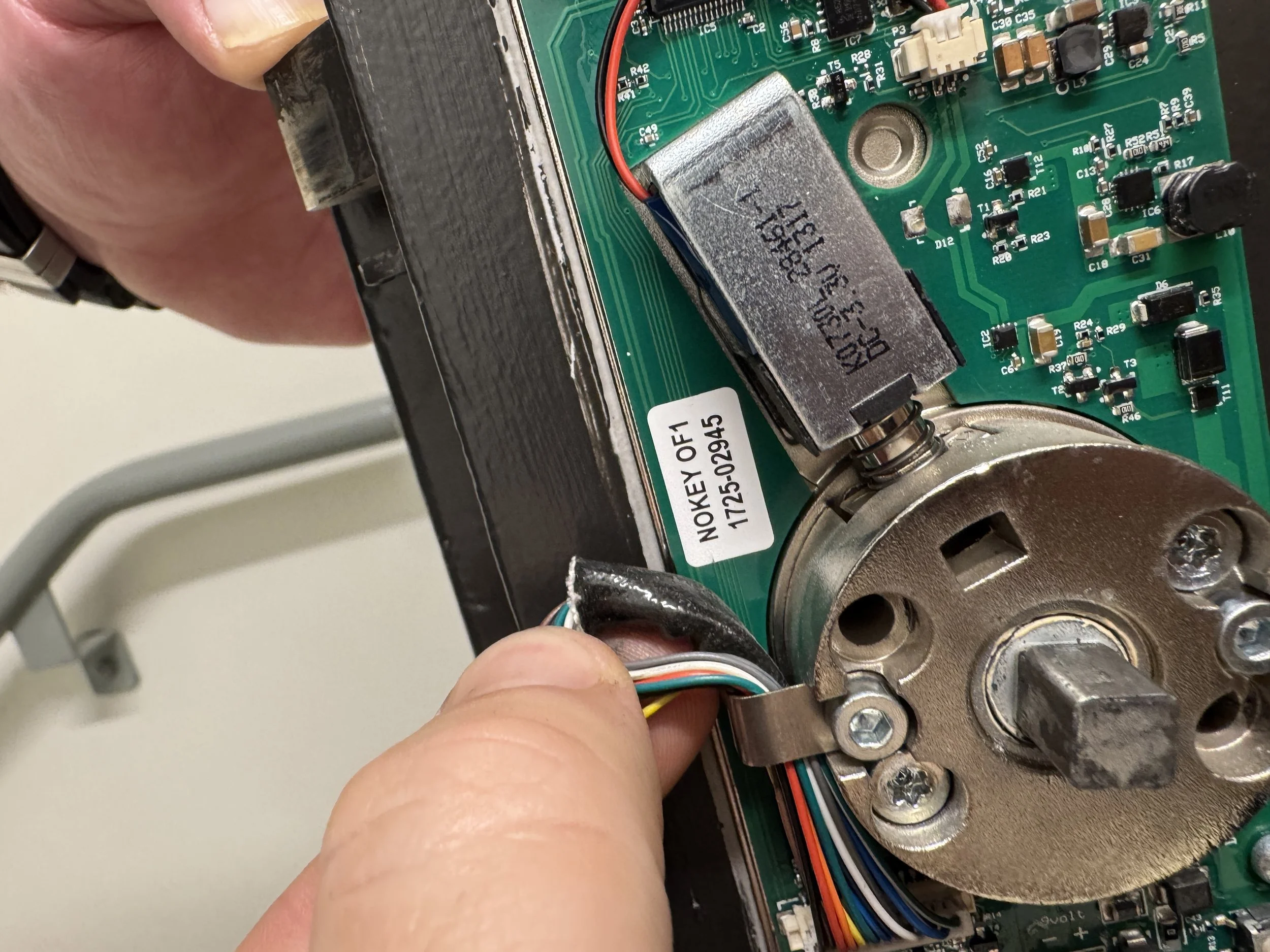 En person som jobber med å isolere og koble til ledninger på innsiden av en elektrisk eller elektronisk enhet.