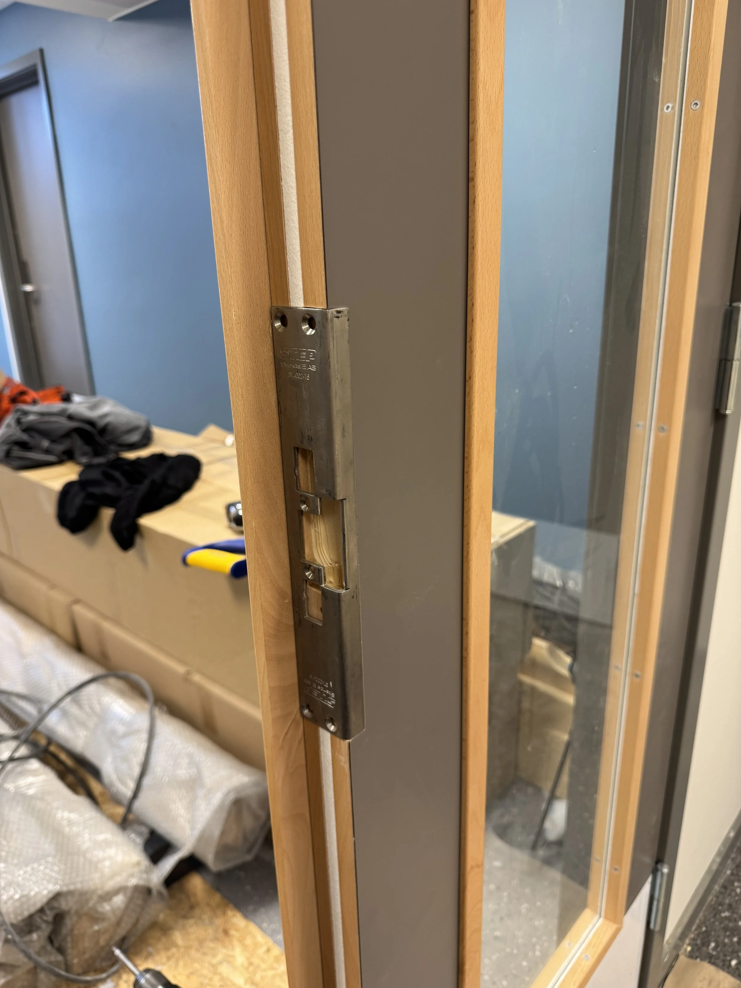 Nærbilde av en tom dørkarm og lås, muligens under installasjon eller reparasjon.