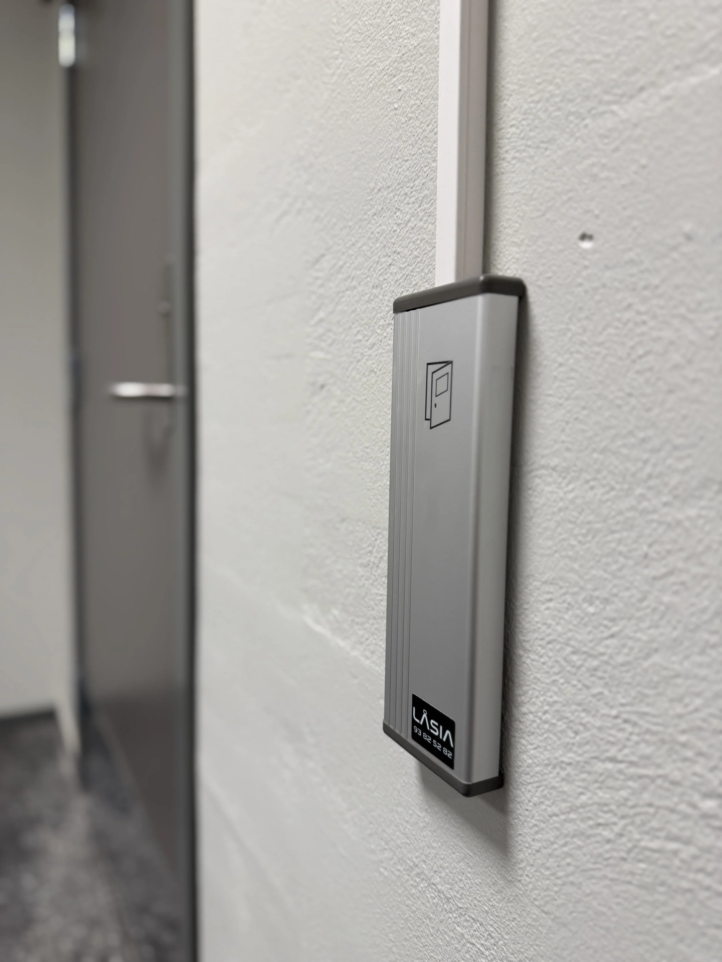 Nærbilde av en veggknapp eller kontrollpanel med en liten skjerm og en logo som sier "VISA", montert på en vegg i et innendørs miljø.