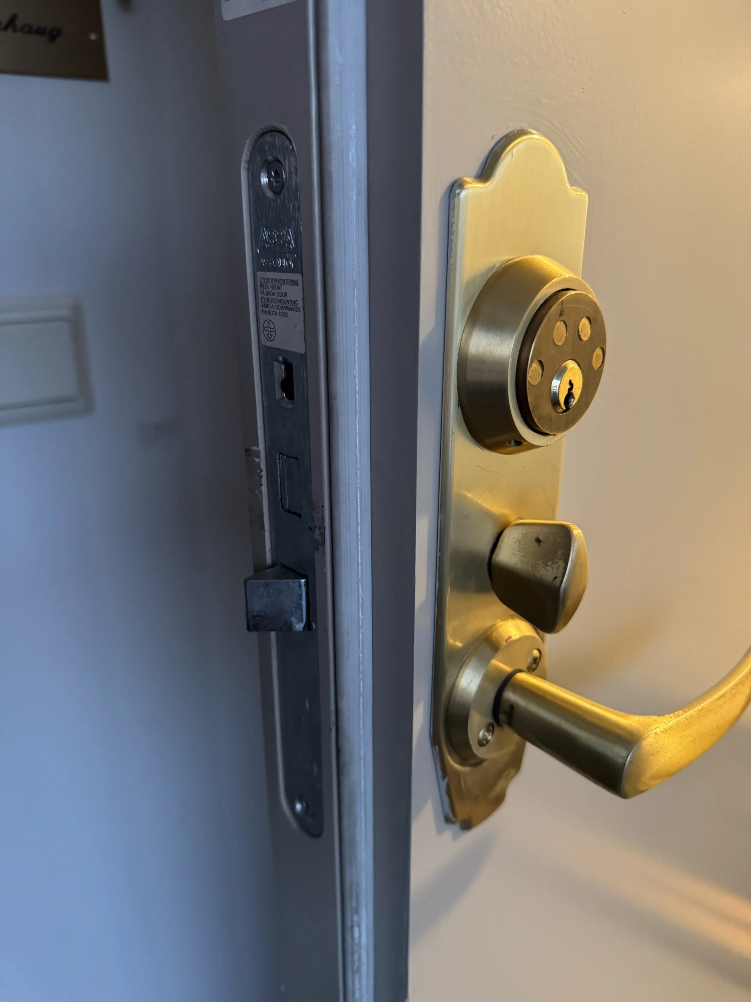 Dørlås og dørhåndtak på en utgangsdør, med synlig nøkkelhull og lås.