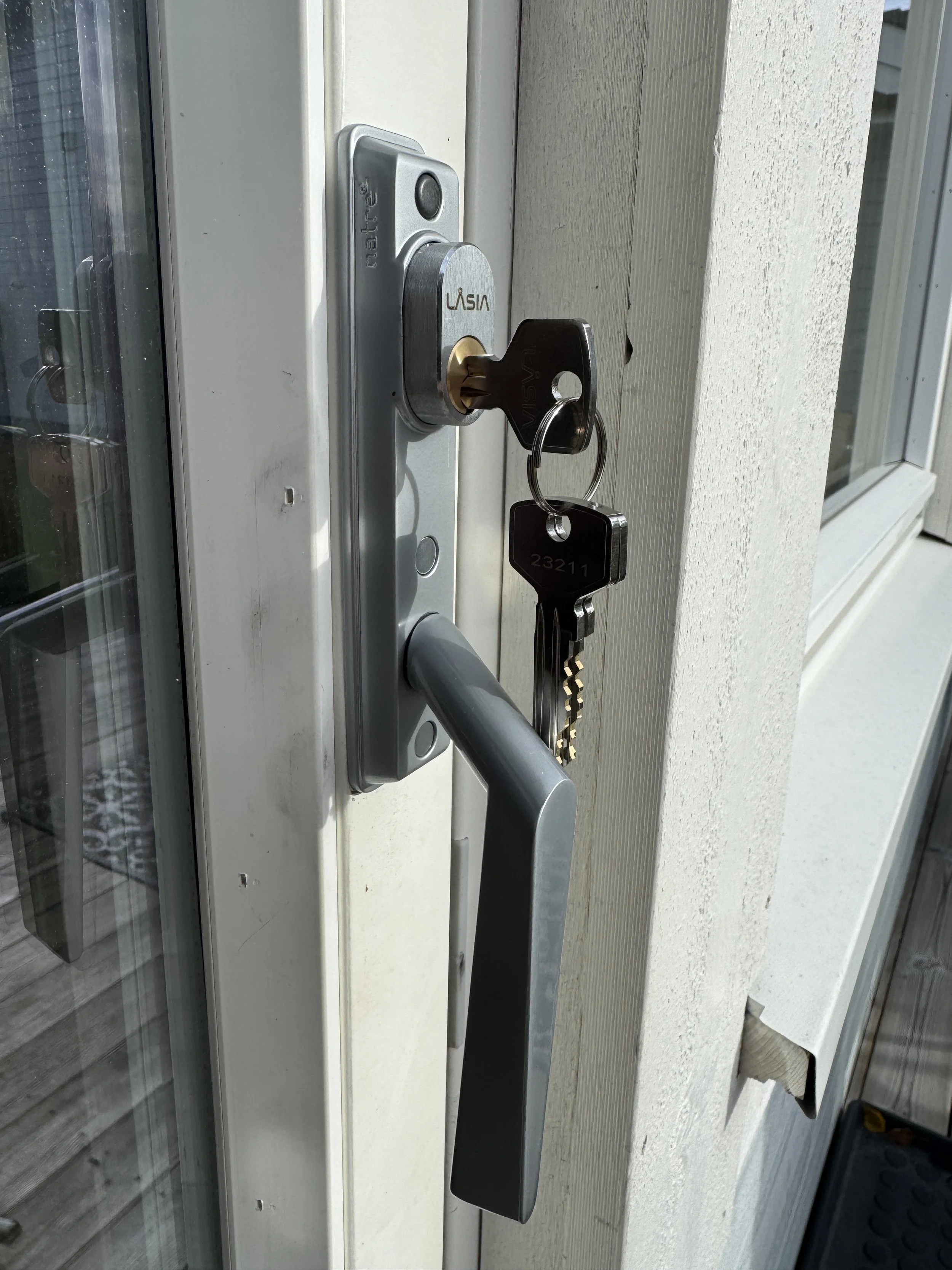 Dør med lås og nøkkel, sett inn i et låsbeslag ved dørkarmen.