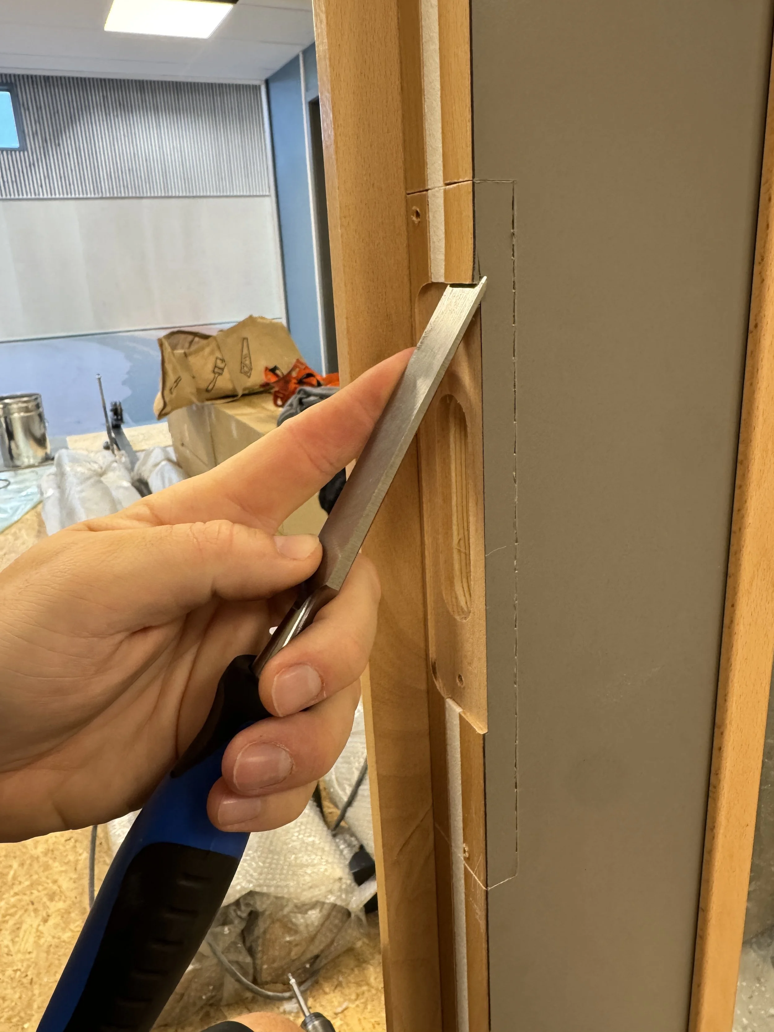 En person holder en metalverktøy mot en treflate under konstruksjonsarbeid.