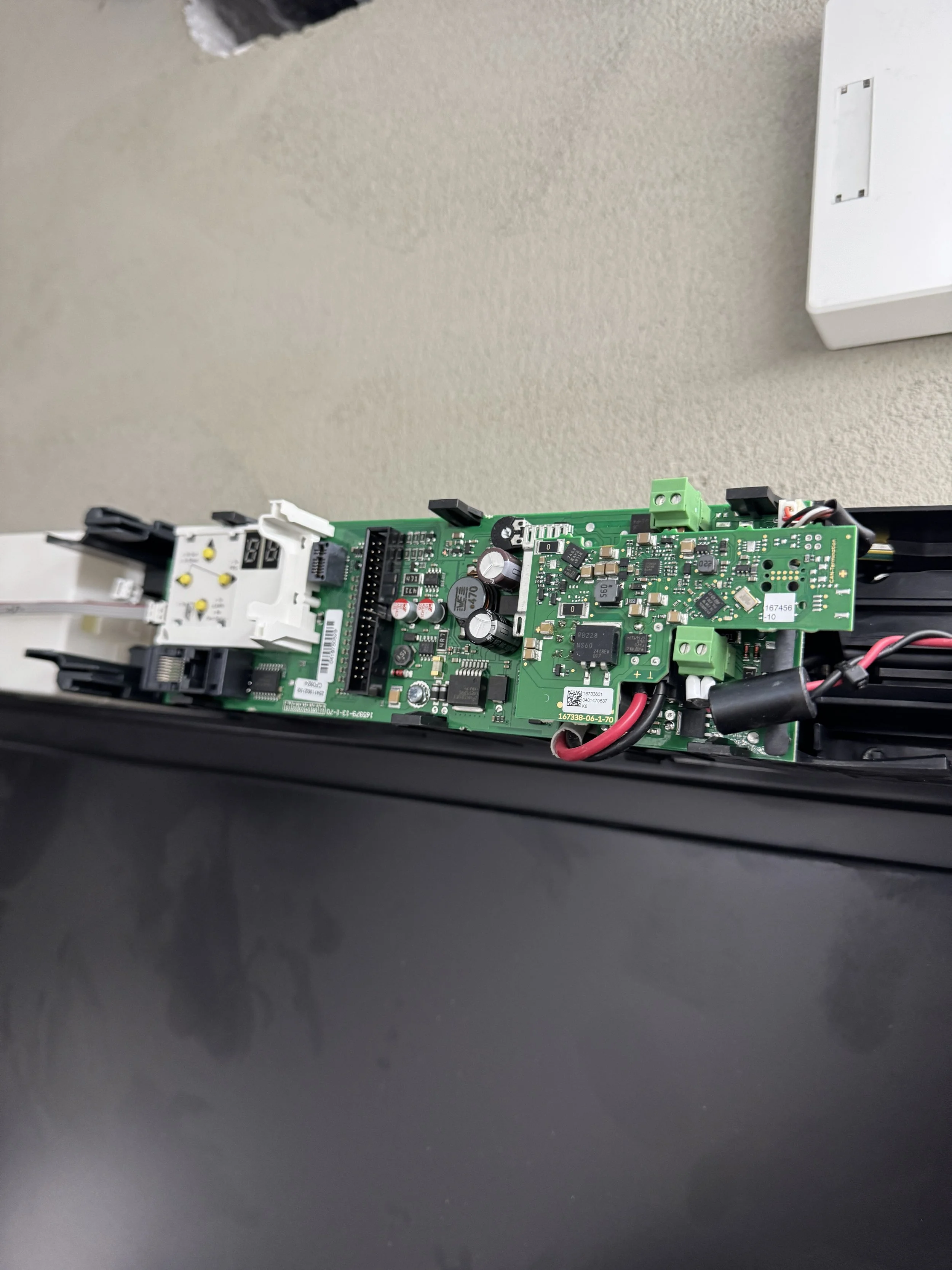 Innside av en elektronisk enhet med en grønn kretskort og flere komponenter, montert i et svart deksel.